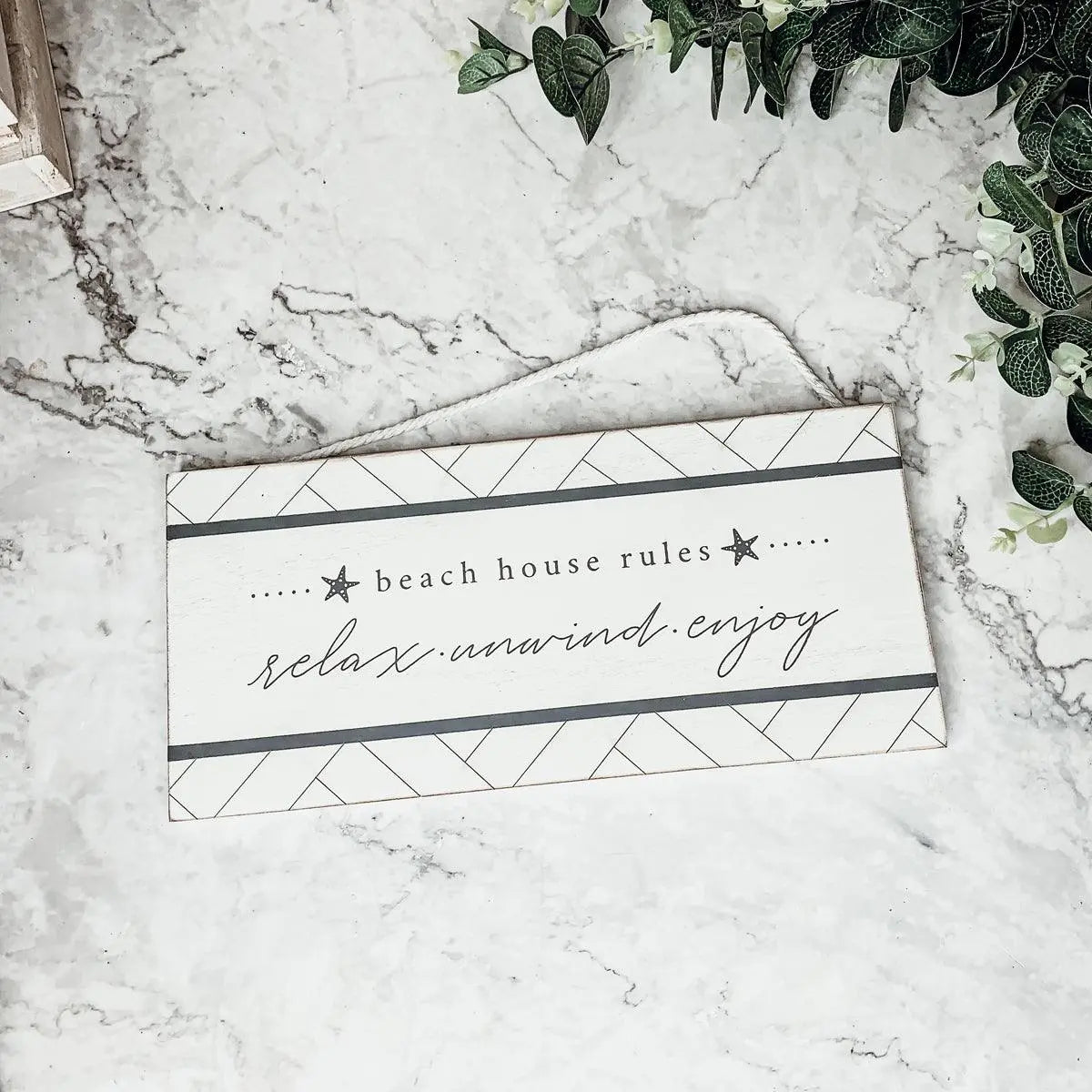 Beach house rules sign with relax unwind enjoy text, farmhouse decor on marble surface