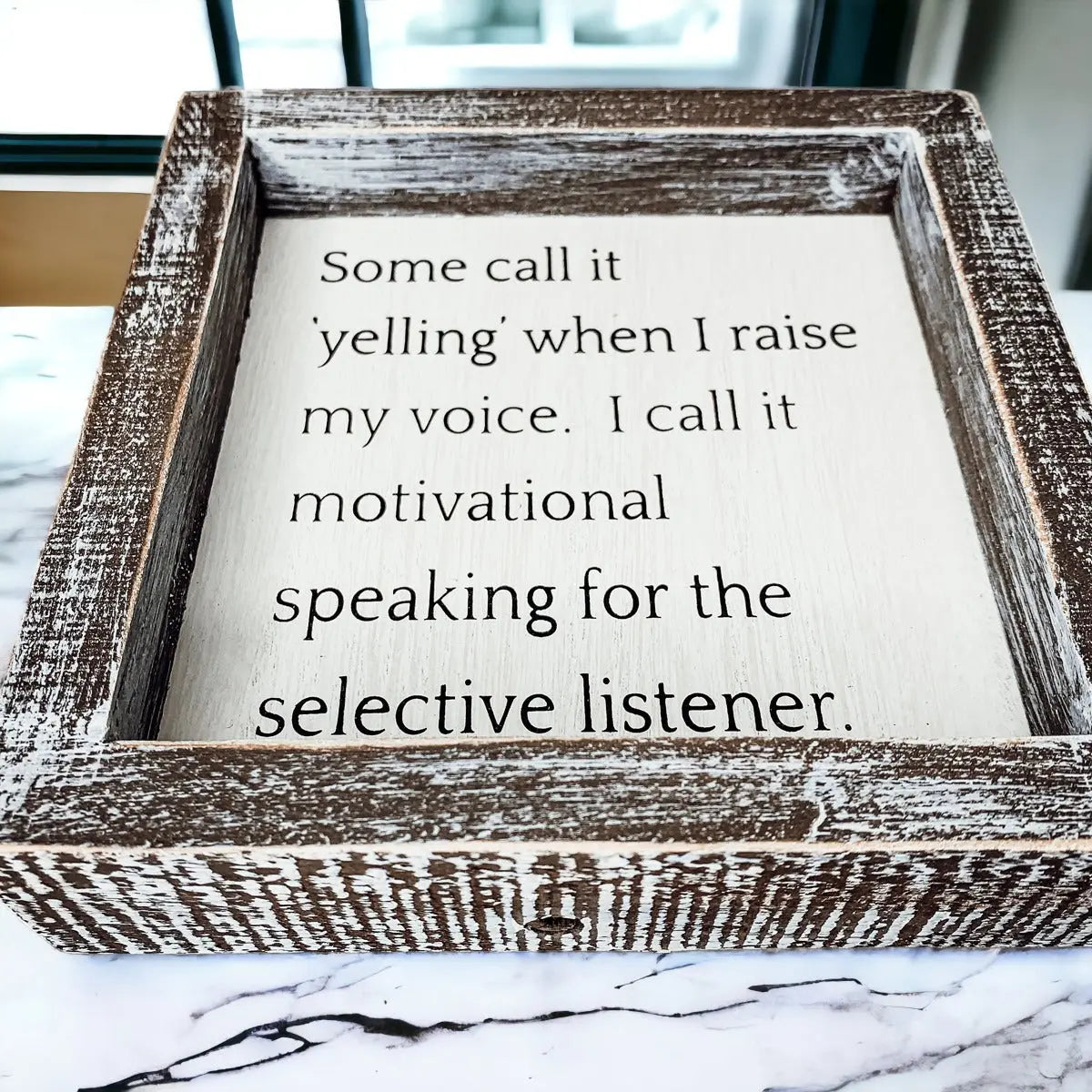 Wooden framed sign with motivational quote on a marble surface
