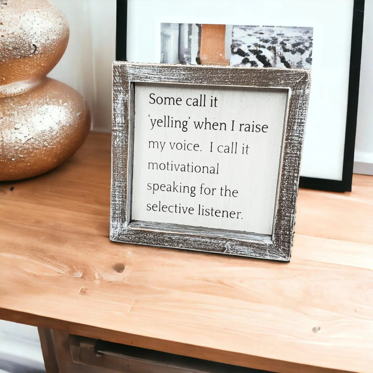 Decorative framed quote on a wooden surface with a textured wall in the background
