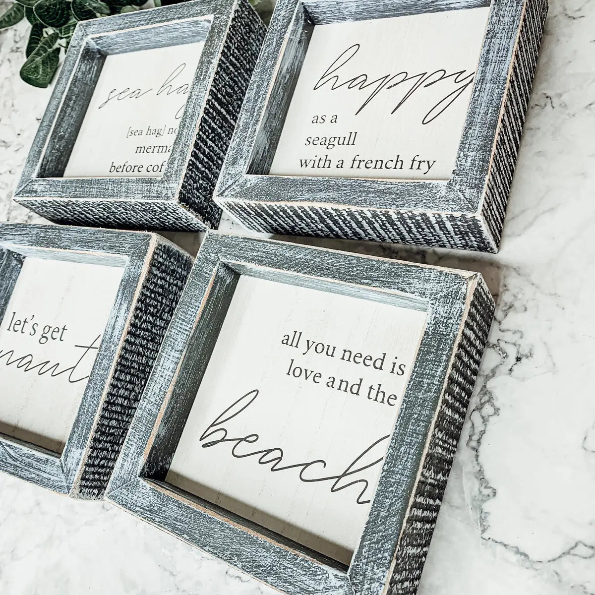 Set of wooden picture frames with printed quotes on a marble surface
