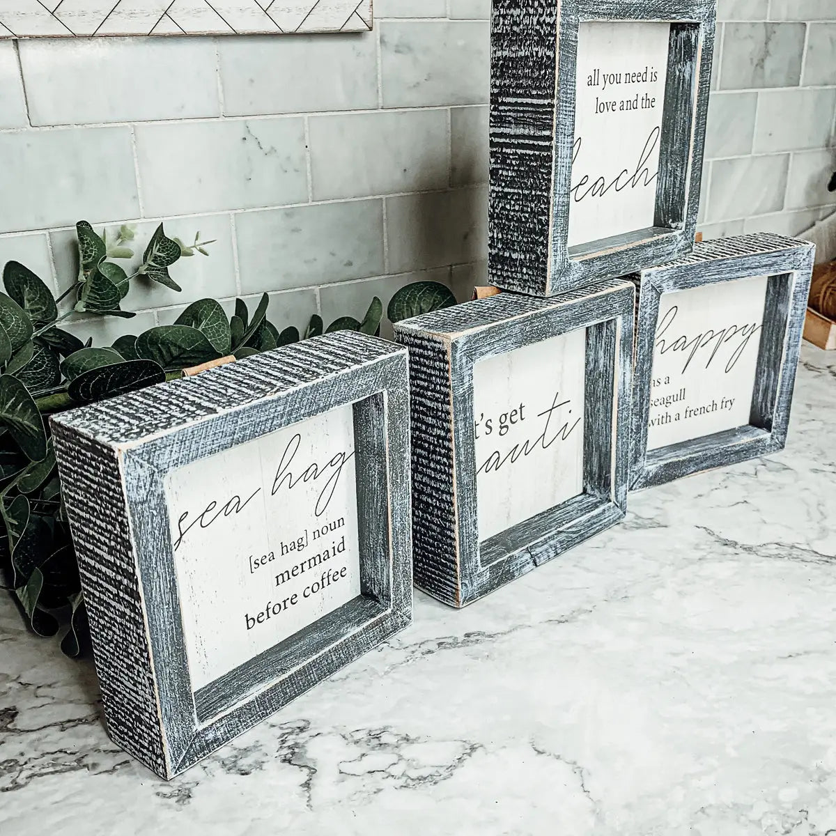 Set of wooden framed signs with text on a marble surface.