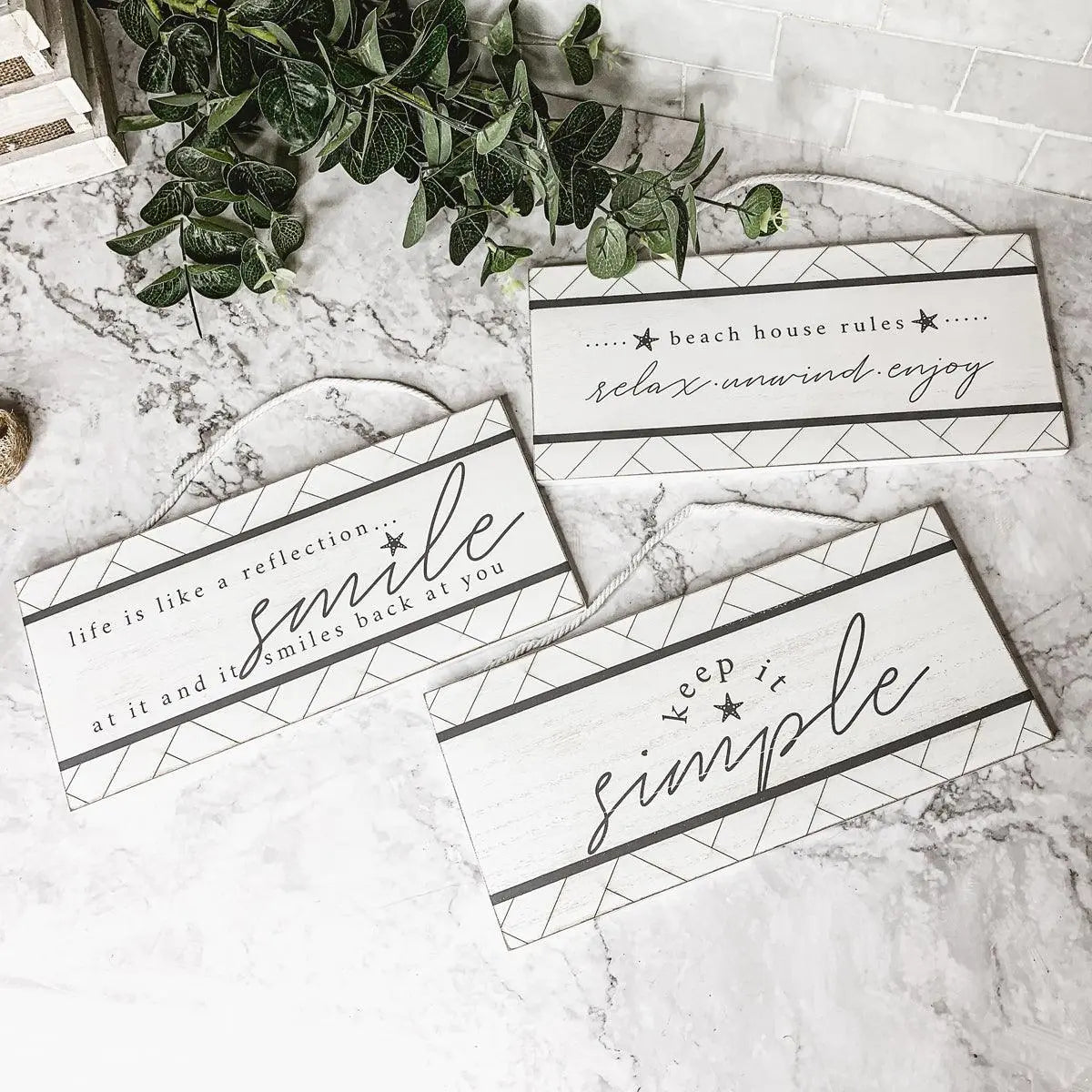 Cozy farmhouse-style wooden signs with motivational phrases on marble surface