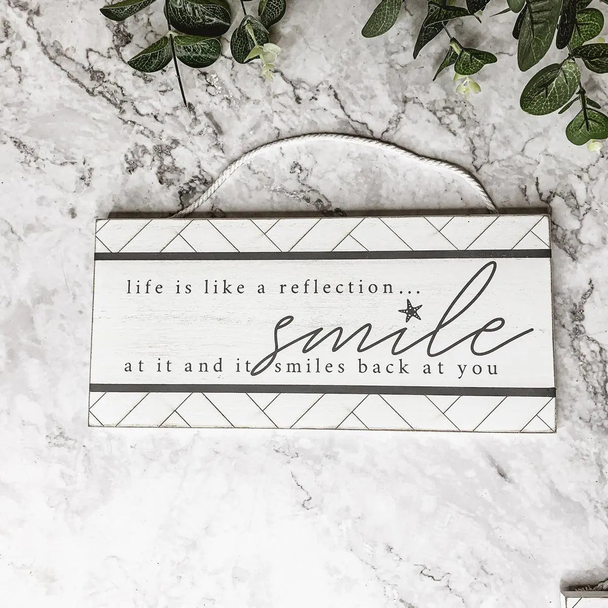 Decorative sign with motivational quote on a marble surface with greenery