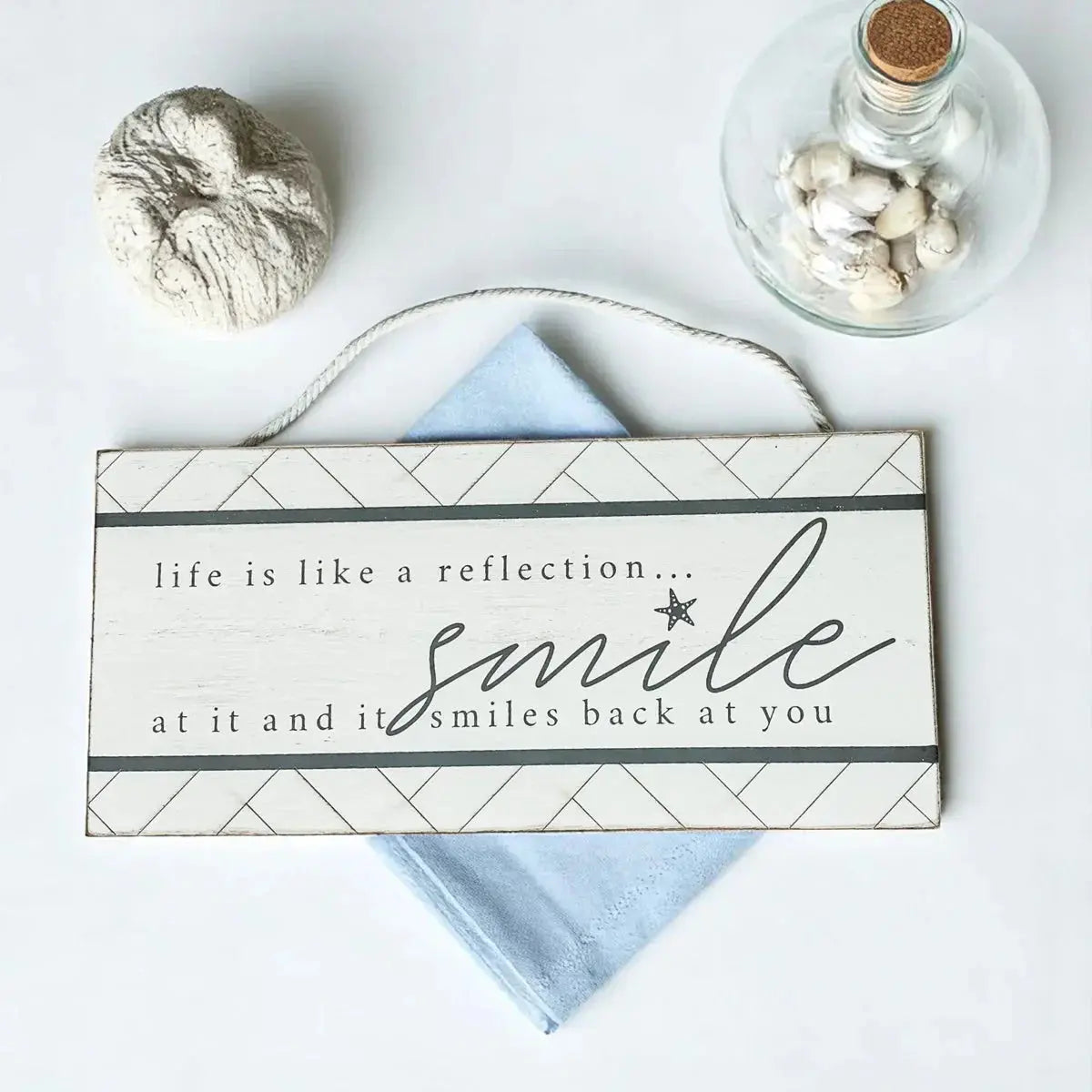 Decorative sign with motivational quote on a white surface with decorative items.