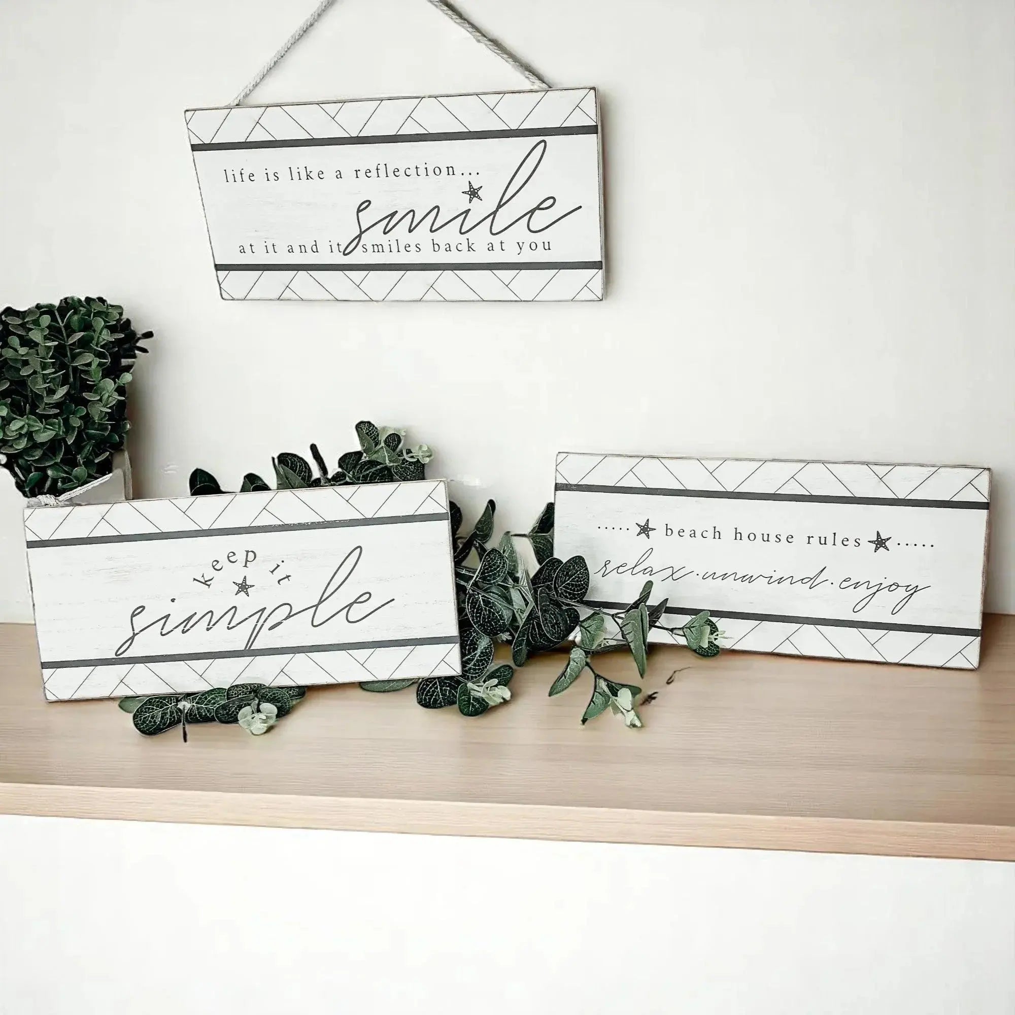 Decorative wooden signs with motivational phrases on a shelf with greenery