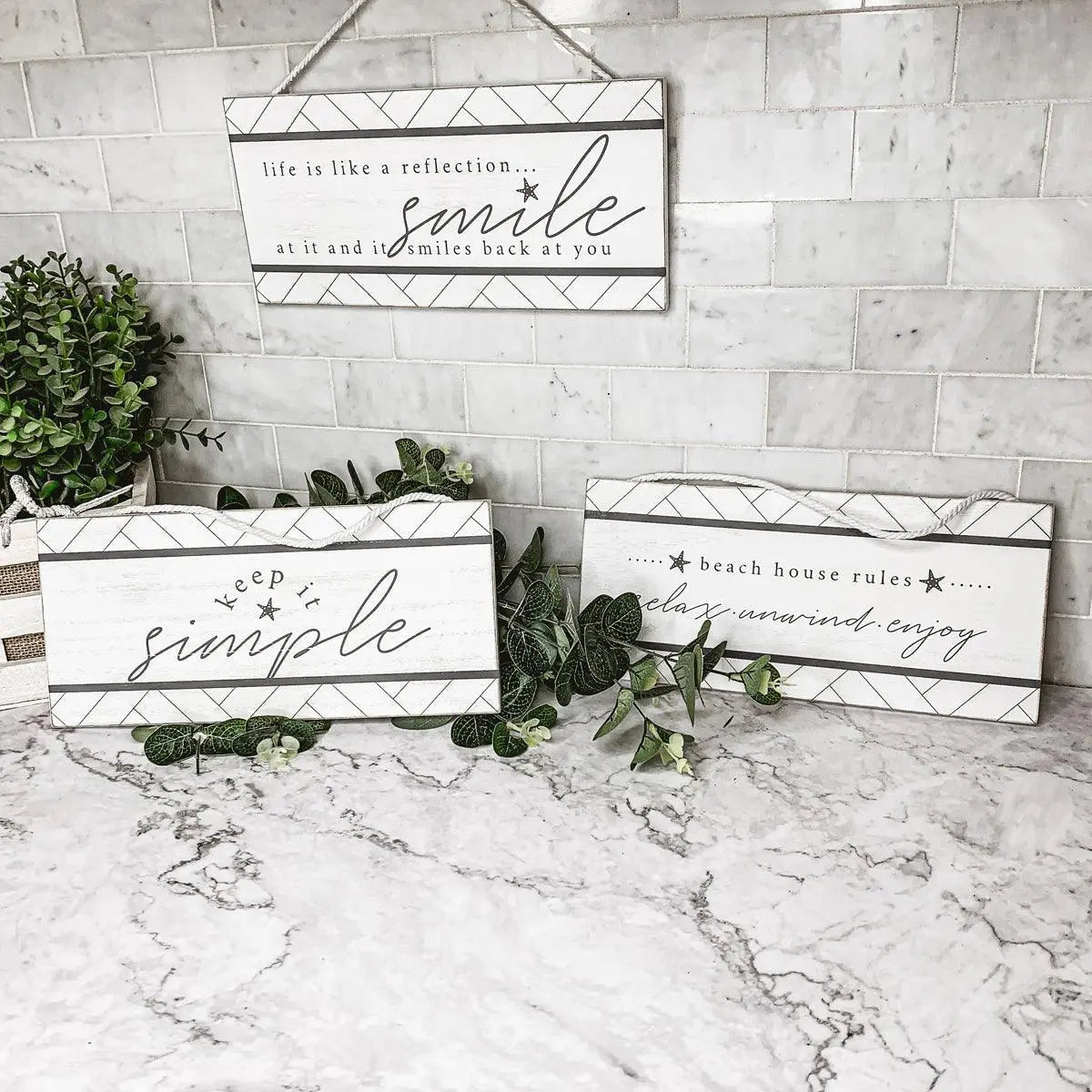 Decorative signs with motivational quotes on a marble surface with plants.