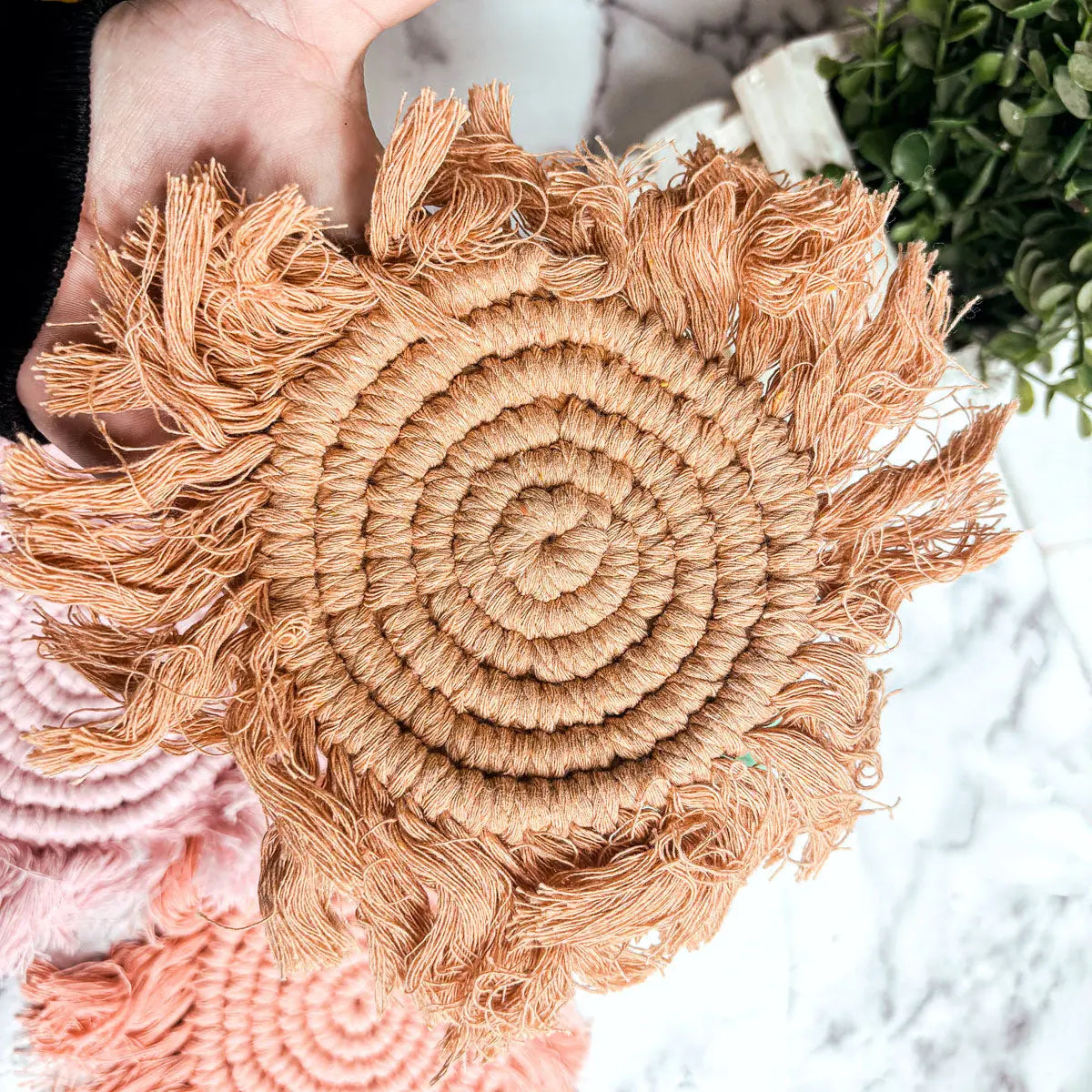 Close-up of a woven decorative item with fringes on a blurred background