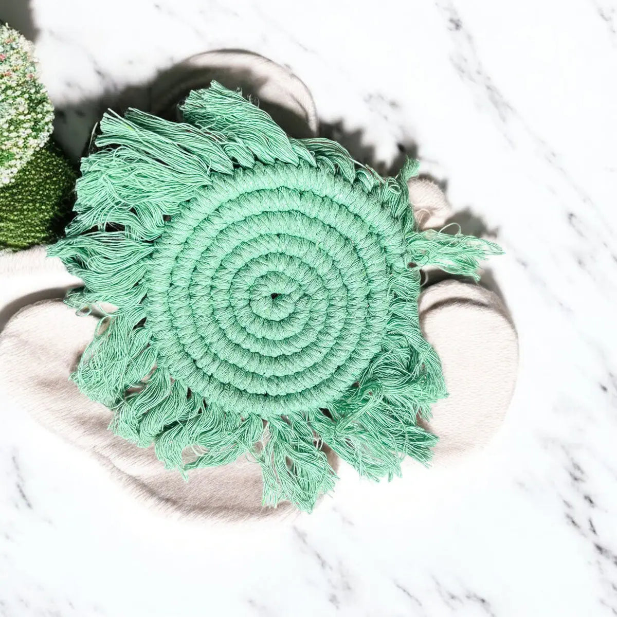 Green woven mat with fringe on a marble surface