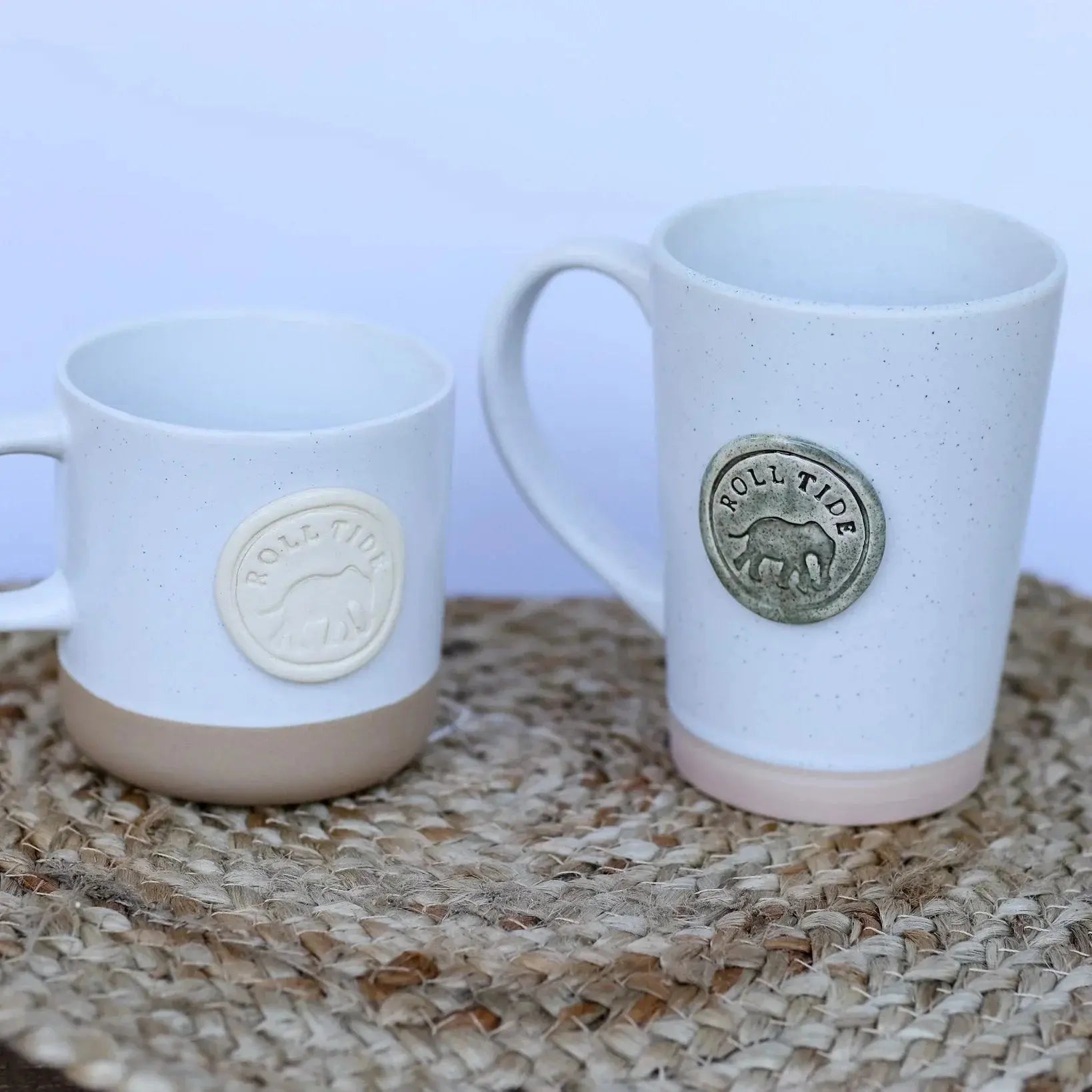 Two speckled ceramic mugs with 'Roll Tide' elephant emblem, cozy farmhouse decor on woven mat