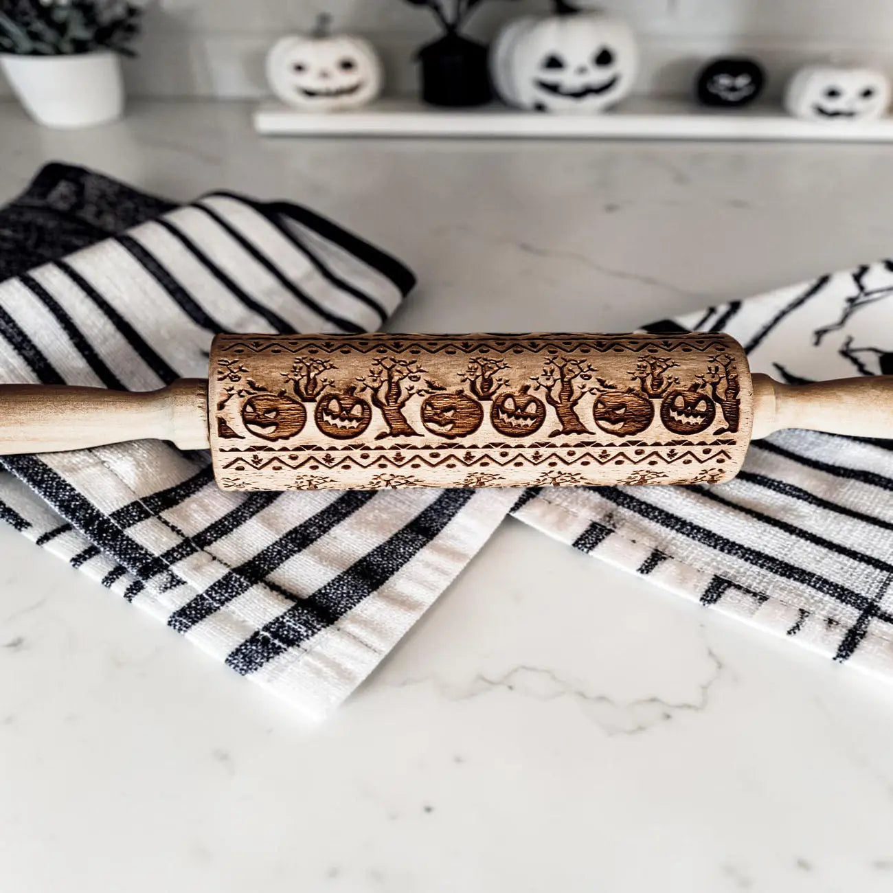 Halloween-themed rolling pin with embossed designs on a marble surface.