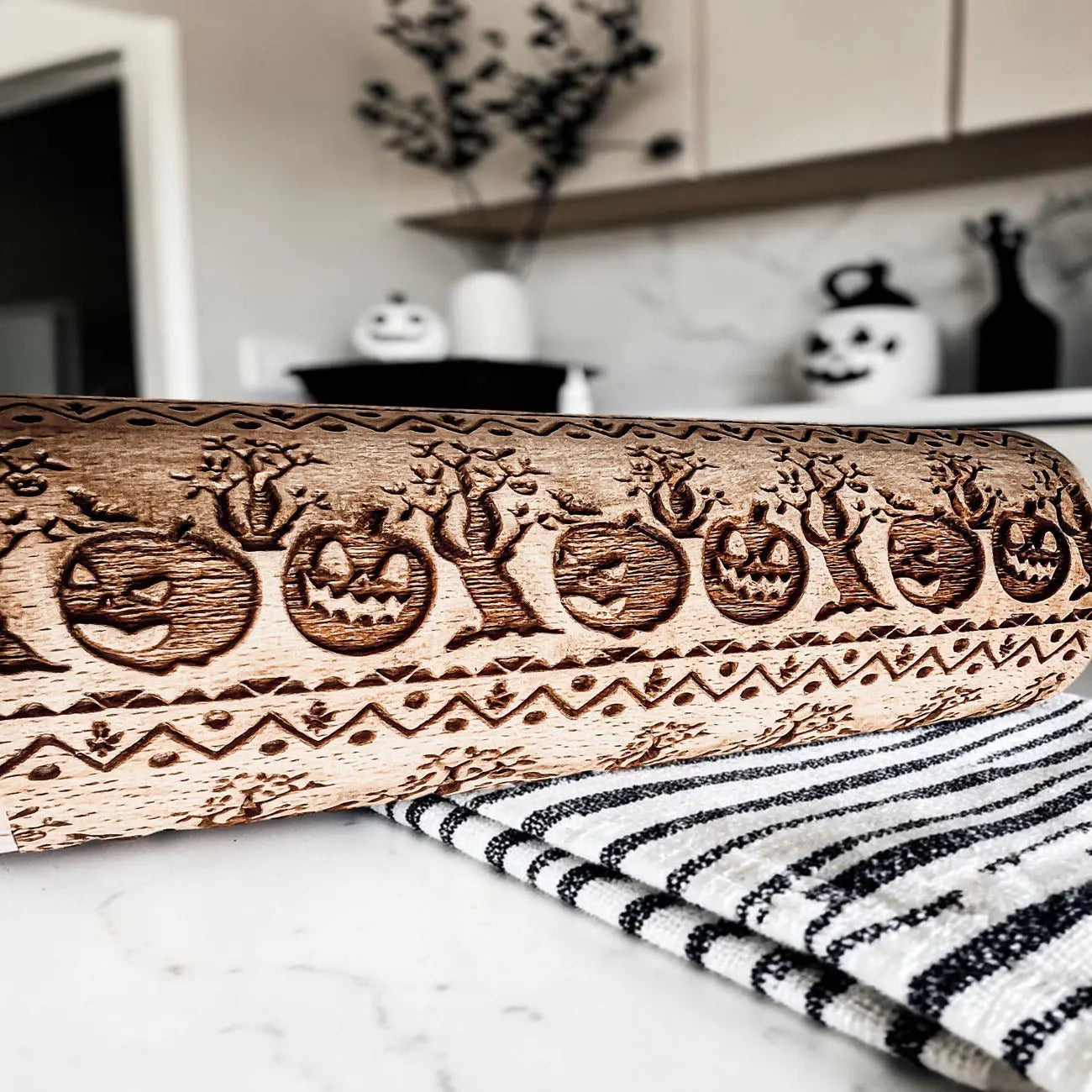 Wooden rolling pin with Halloween designs on a kitchen counter