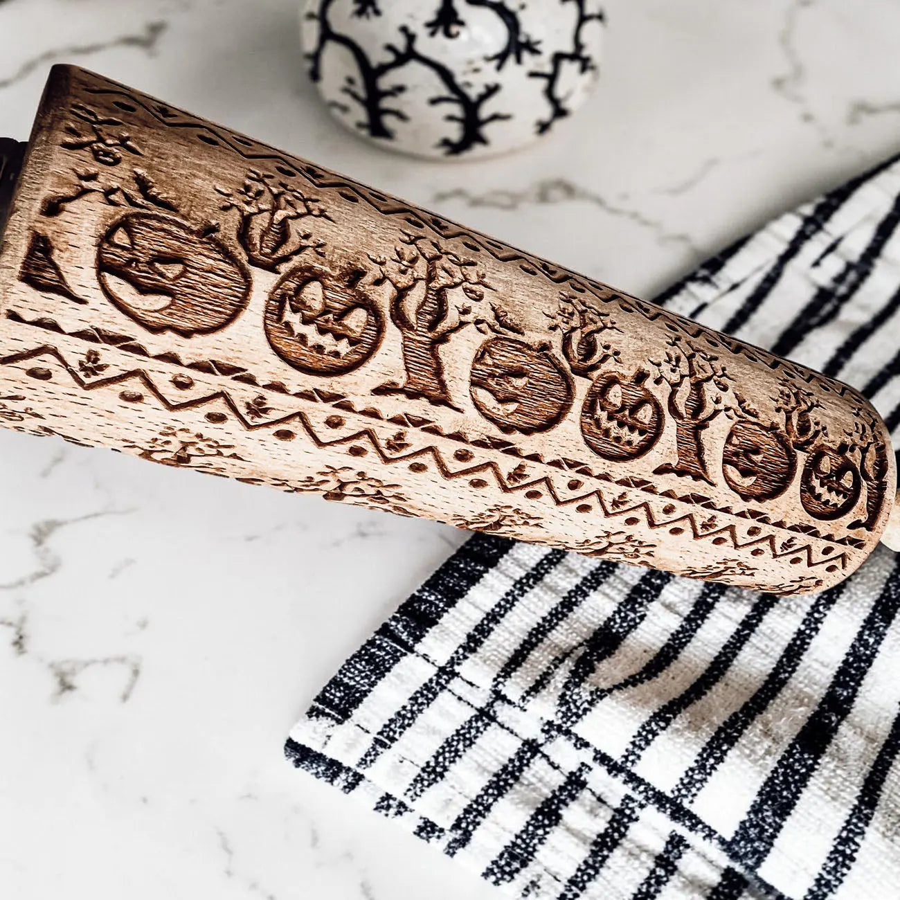 Wooden embossing tool with Halloween designs on a marble surface