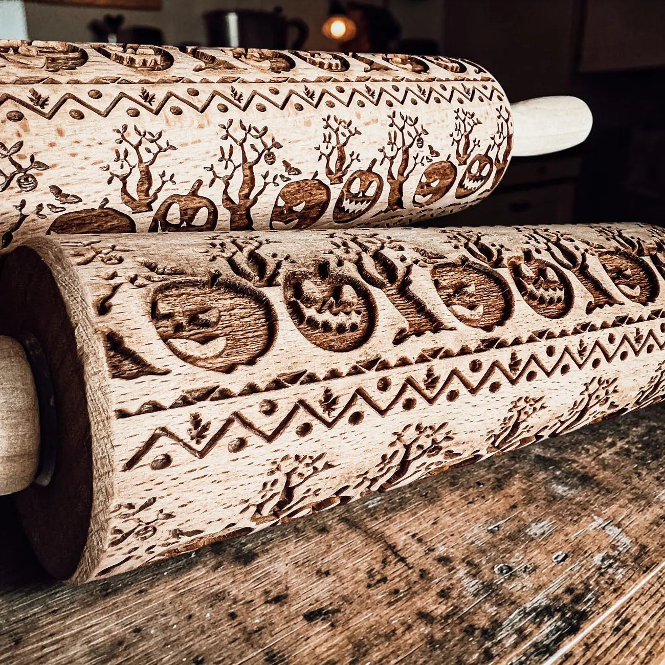 Two wooden embossing rolling pins with engraved designs on a wooden surface.