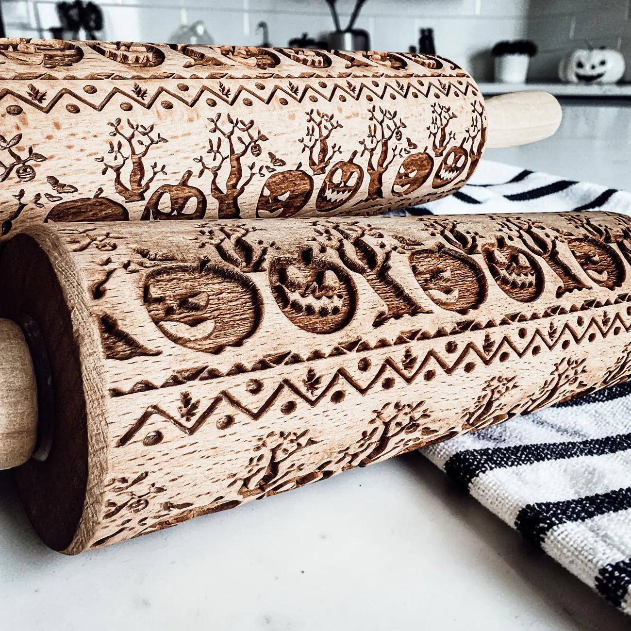 Two wooden rolling pins with embossed designs on a kitchen counter.