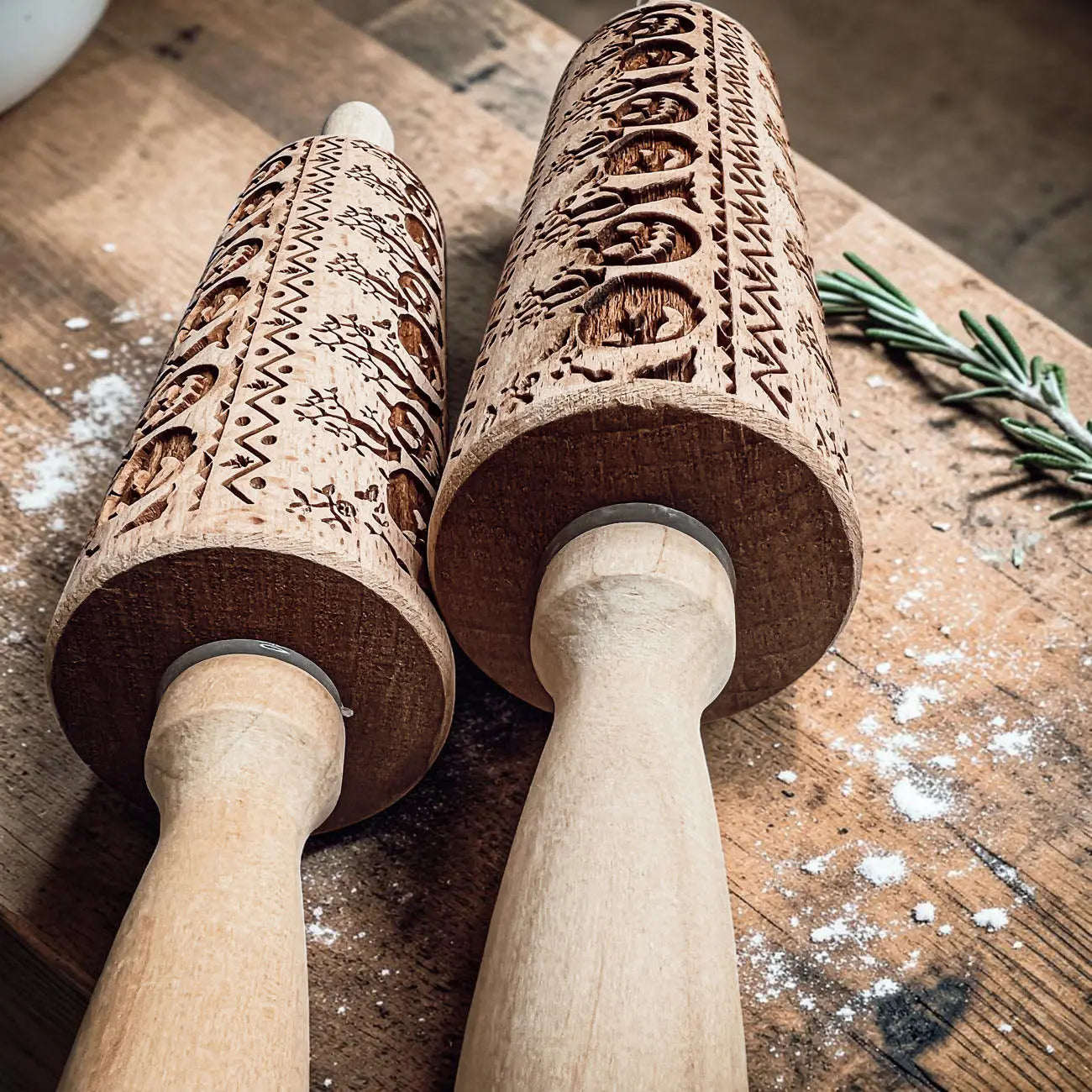 Two wooden embossing rolling pins with intricate patterns on a wooden surface.