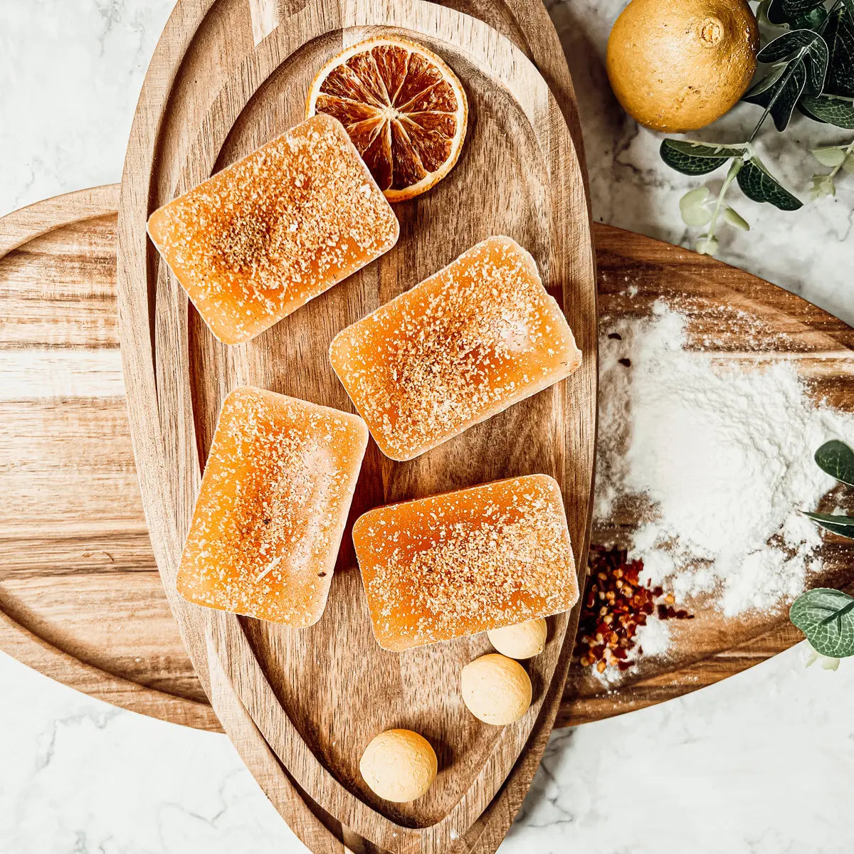 Rectangular orange-scented candles on a wooden cutting board with oranges and spices.