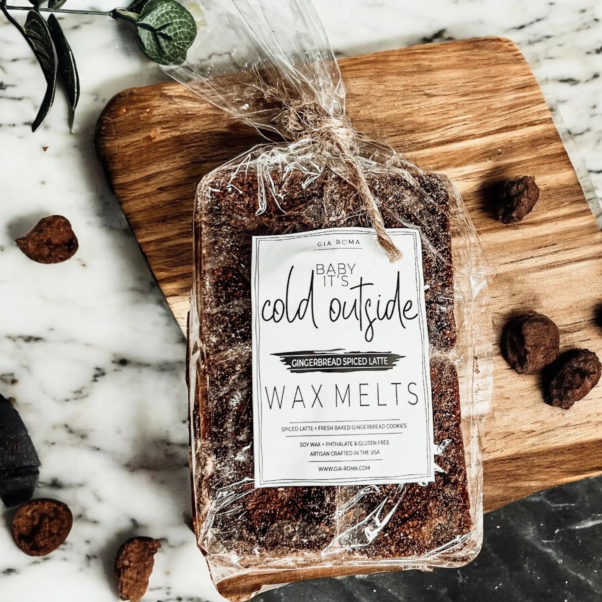 Packaged wax melts labeled 'Cold Outside' on a wooden cutting board with gingerbread cookies.