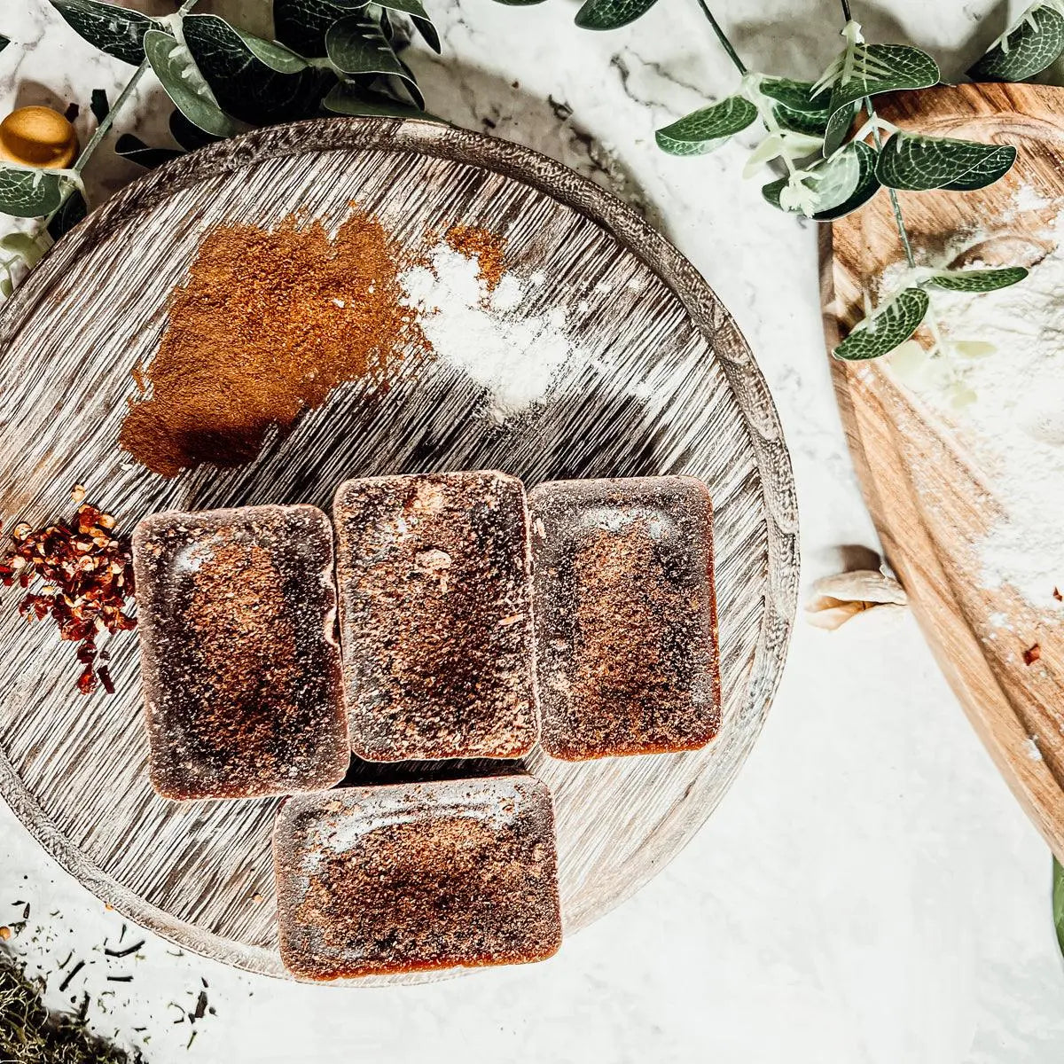 Square brownies on a wooden board with flour and spices on a light background