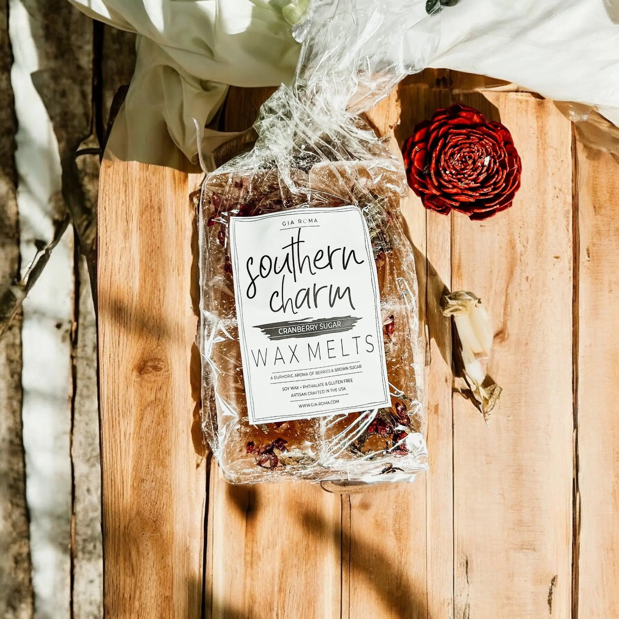 Packaged wax melts labeled 'Southern Charm' on a wooden surface with a red rose.