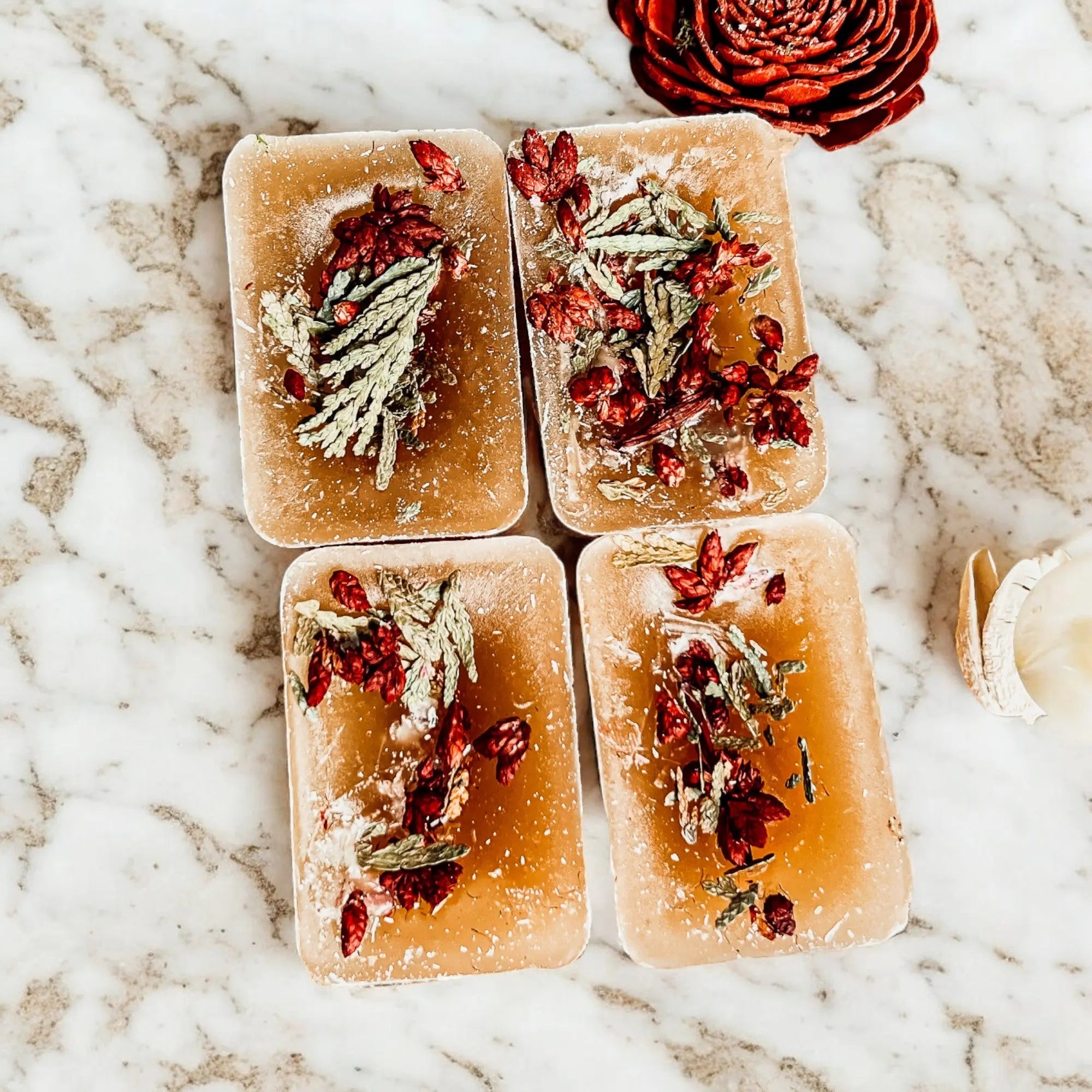 Four rectangular soap bars with dried herbs on a marble surface