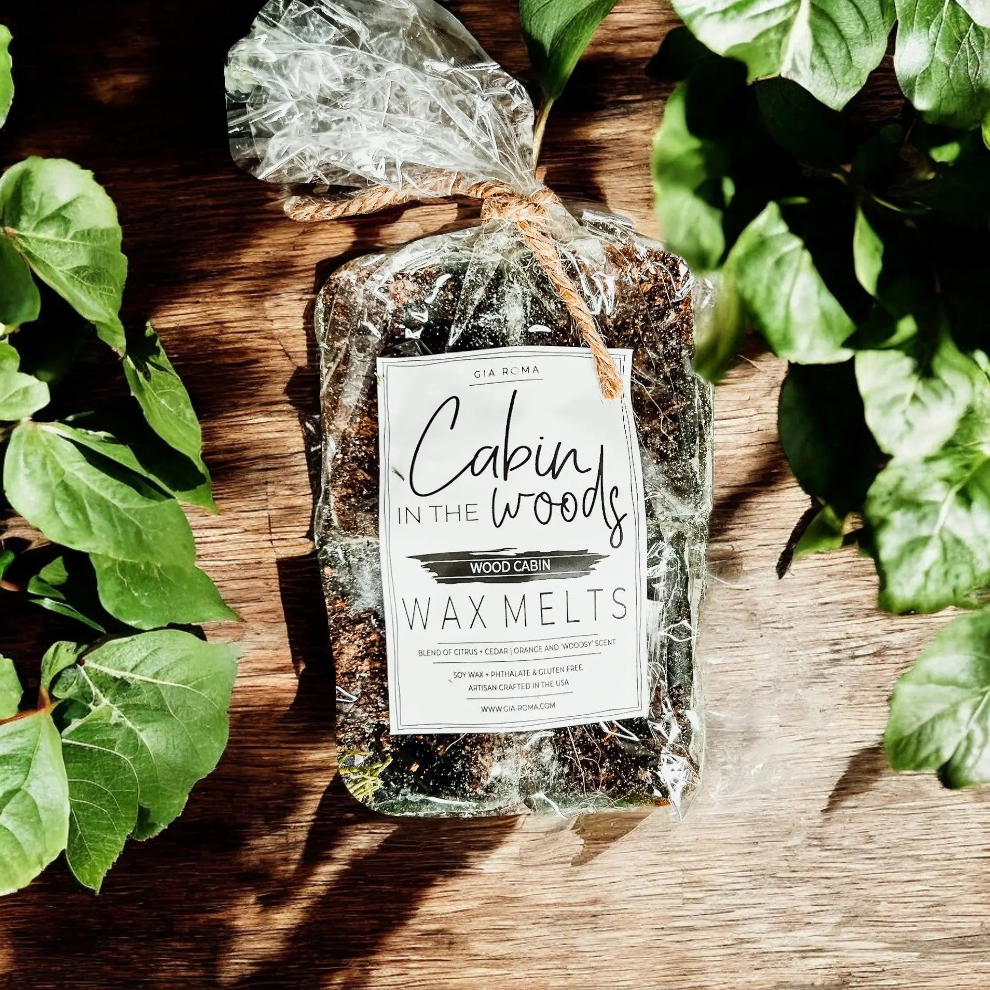 Pack of Cabin in the Woods wax melts on a wooden surface with green leaves around