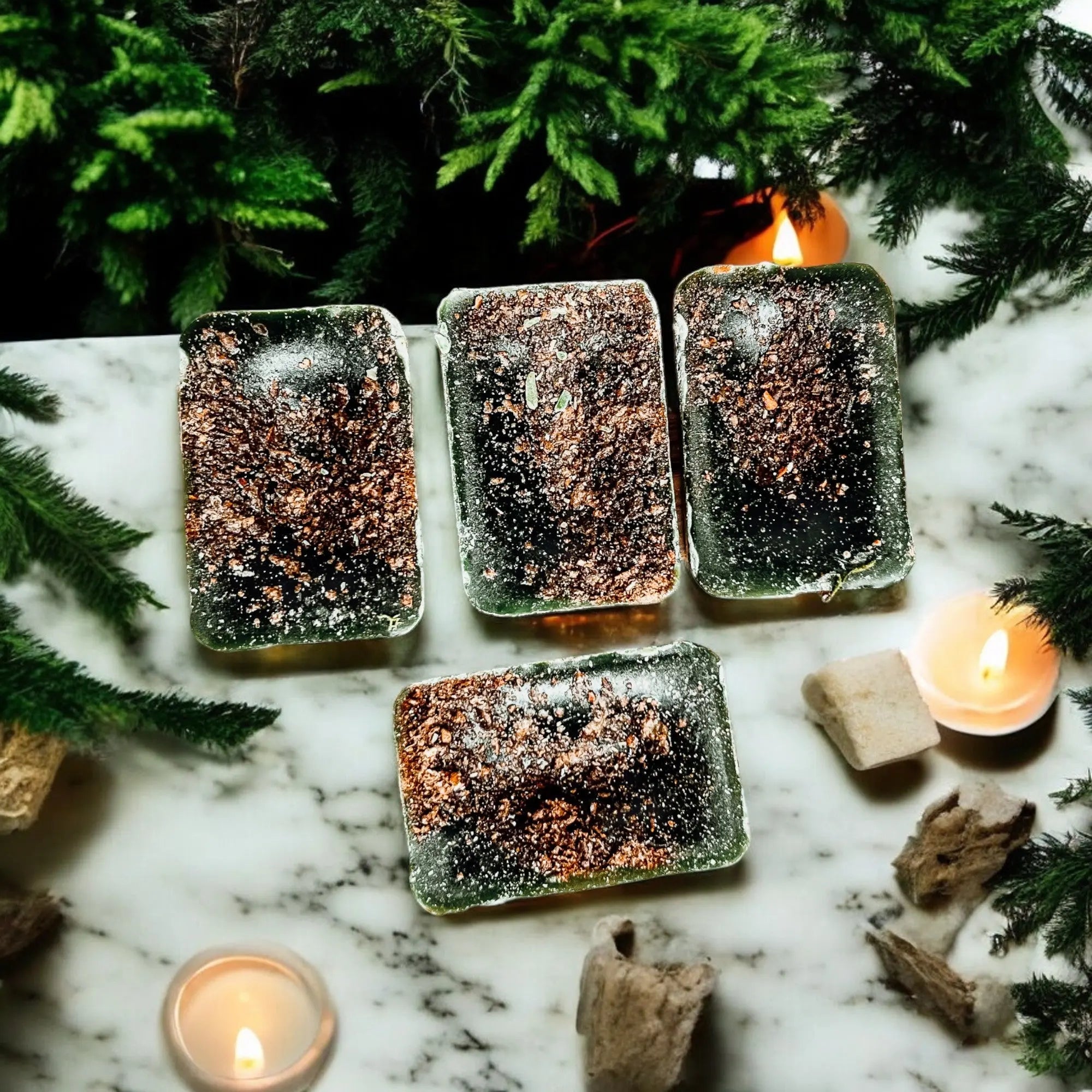 Decorative ice blocks with copper glitter on a marble surface with candles and greenery.
