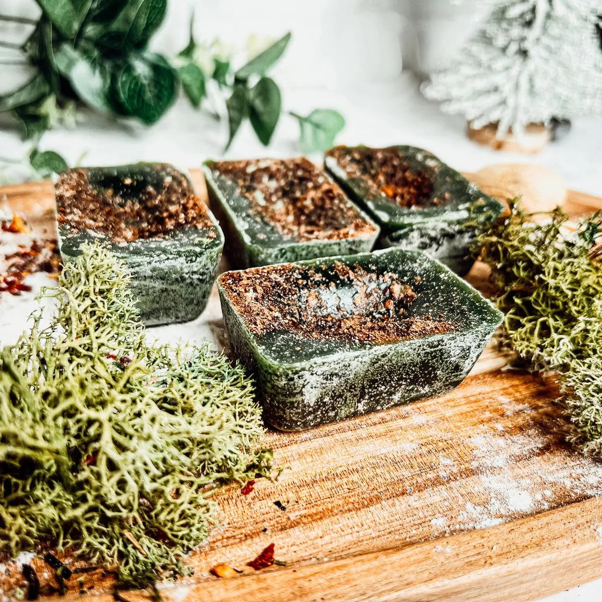 Green soap bars on a wooden surface with plants in the background