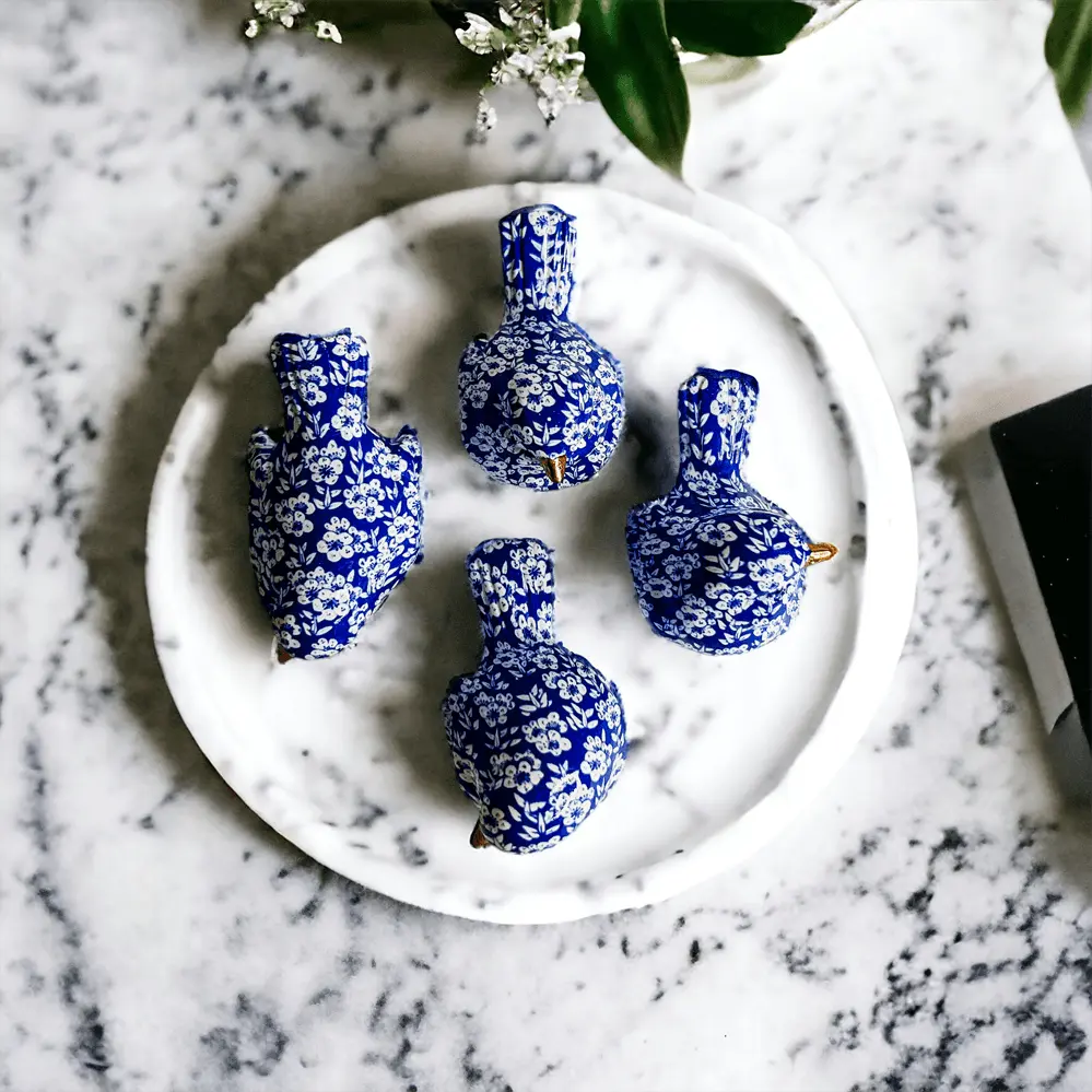 Set of blue and white decorative vases on a marble surface with greenery.