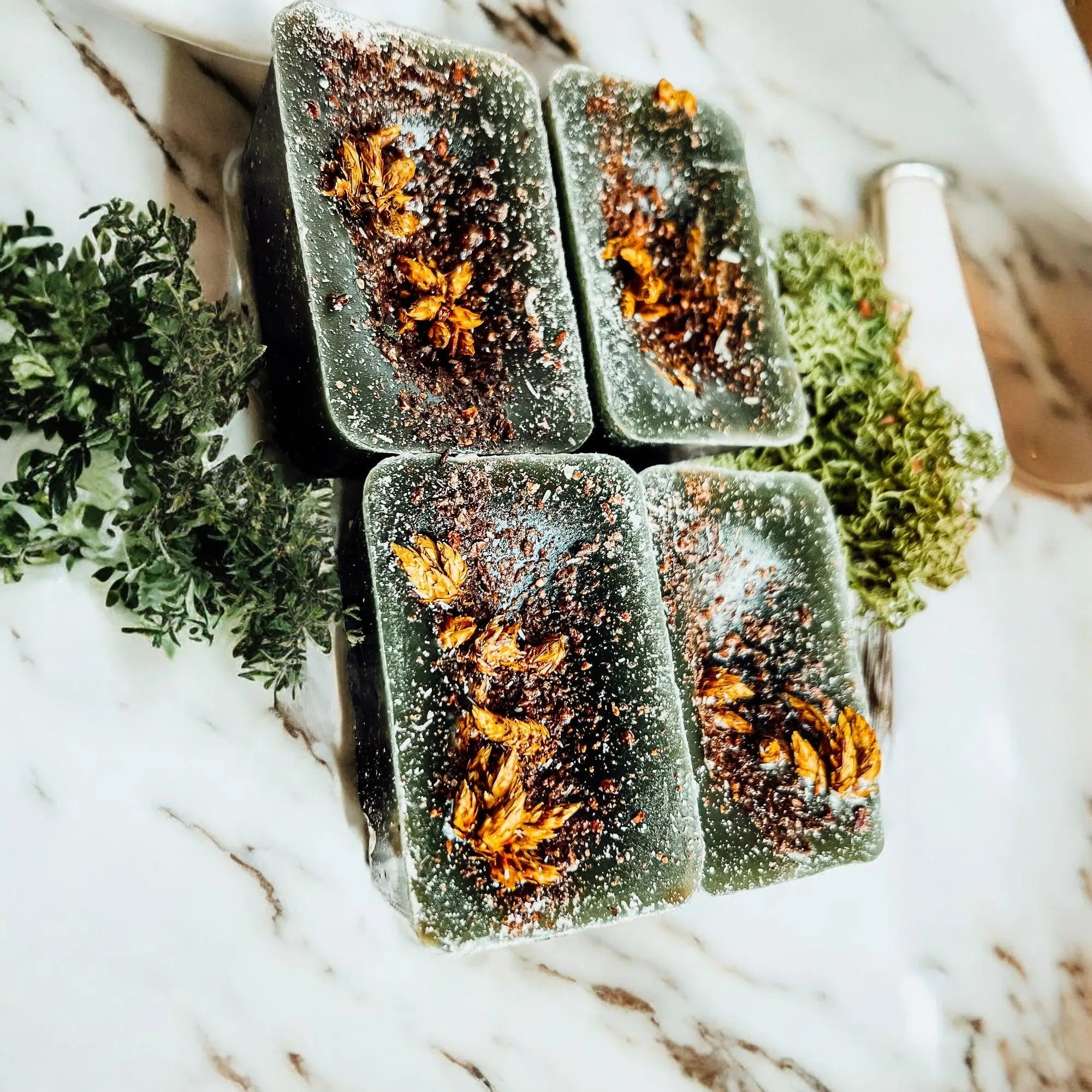 Four rectangular soap bars with natural ingredients on a marble surface