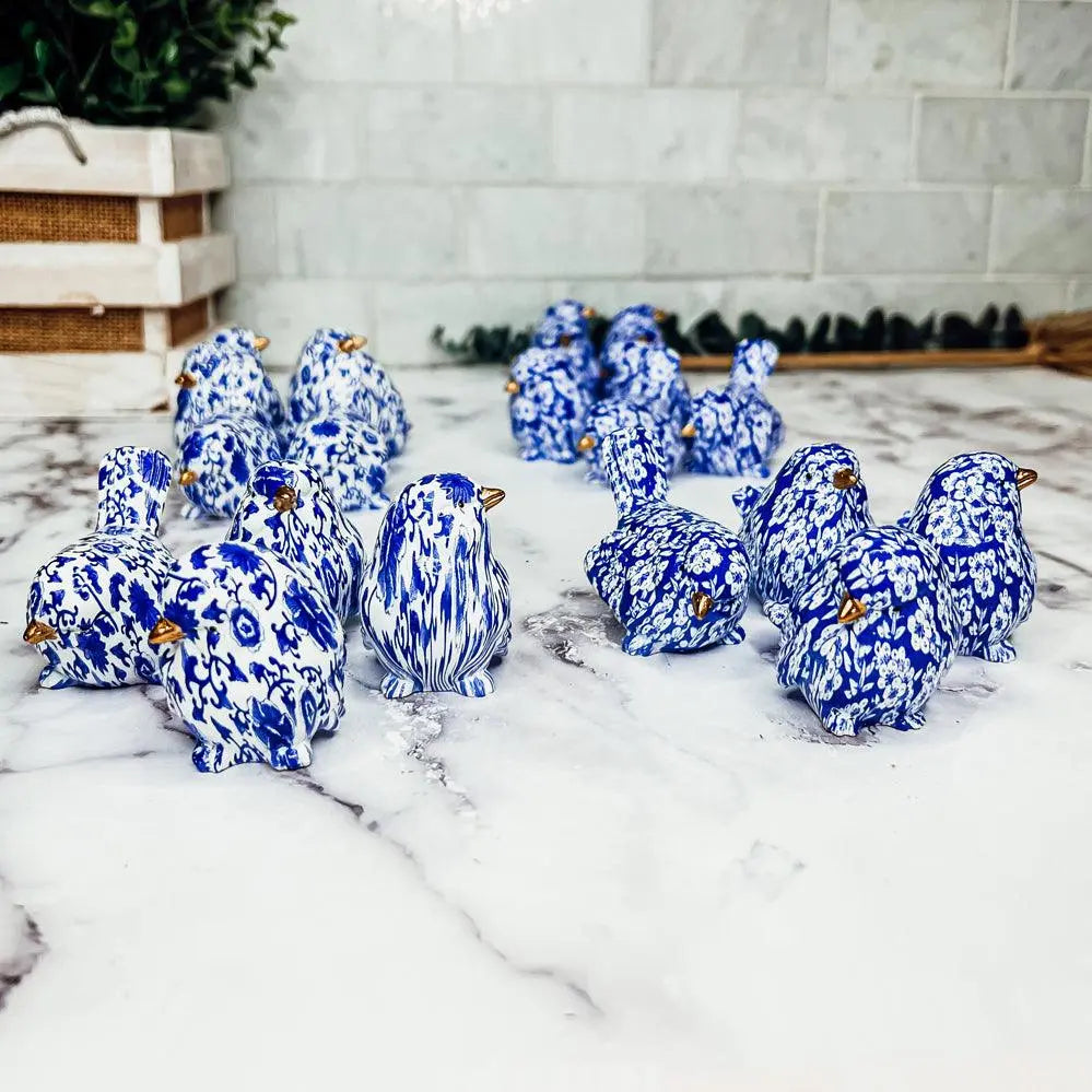 Blue and white ceramic penguins on a marble surface with a light gray tiled wall in the background.