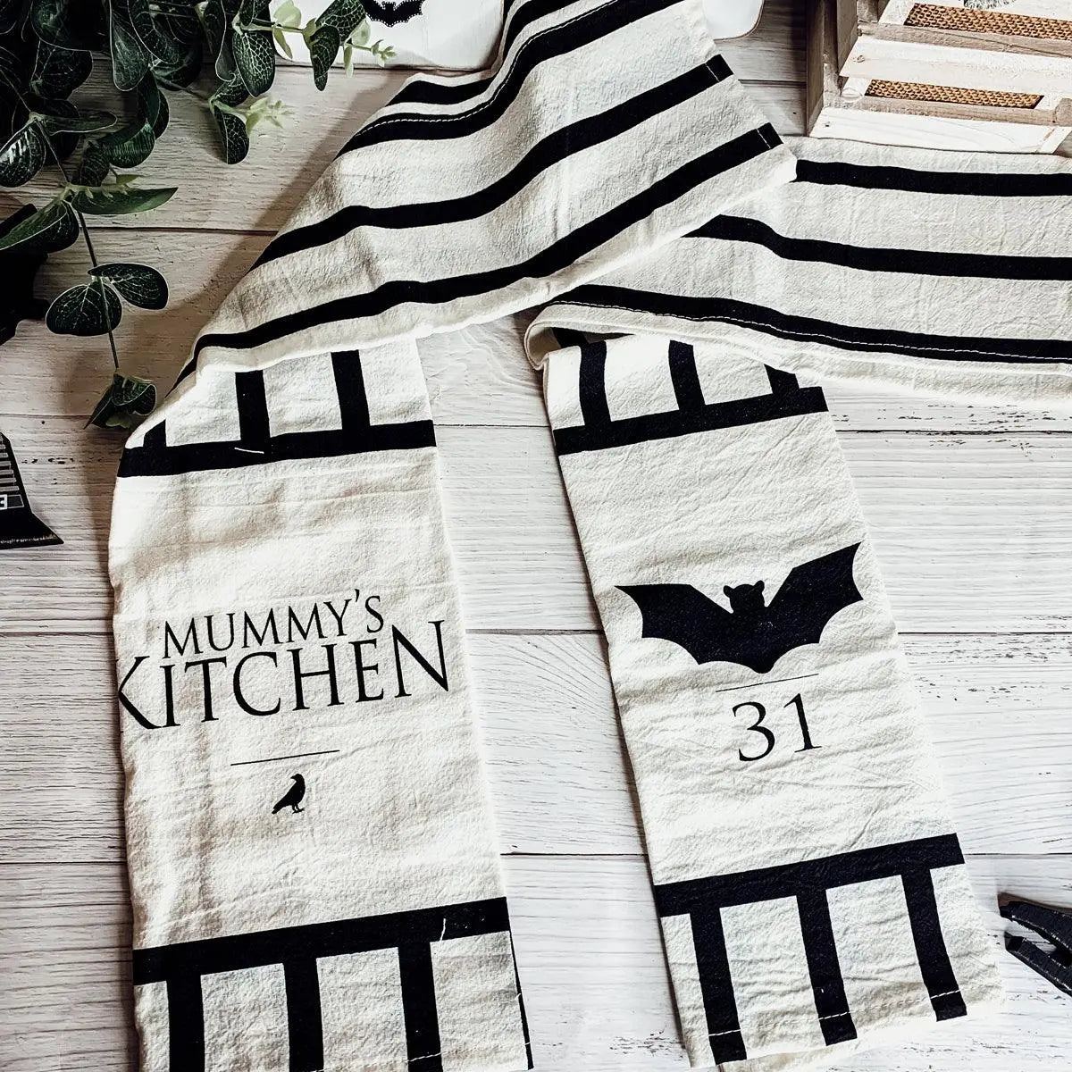 Two Halloween-themed towels on a wooden surface with decorative elements.