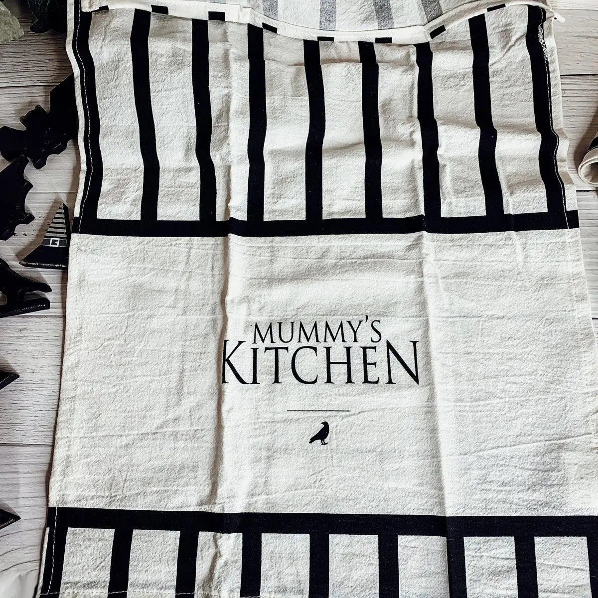 Kitchen towel with 'Mummy's Kitchen' text and black bird graphic on a wooden surface
