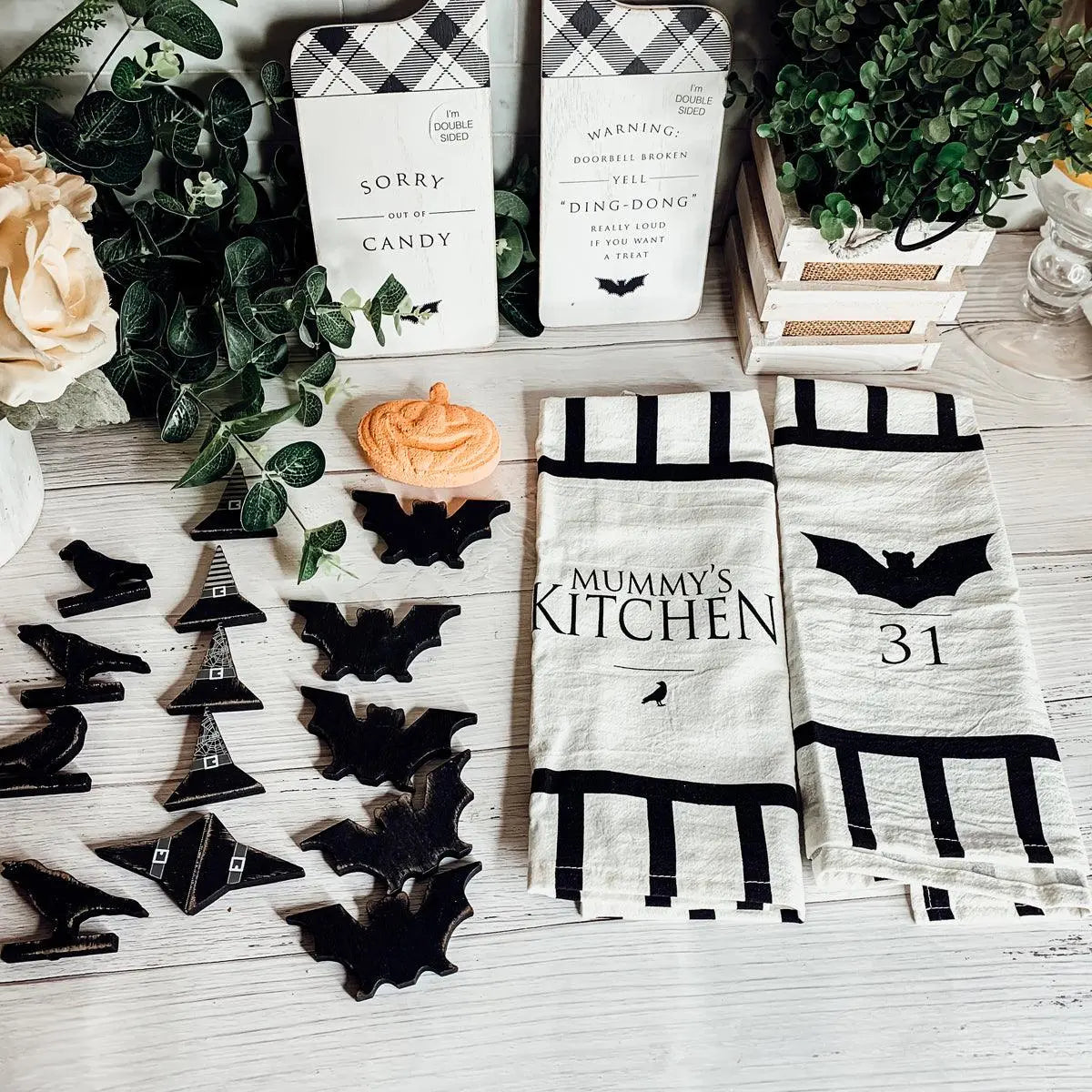 Halloween-themed kitchen towels with decorative items on a wooden surface.