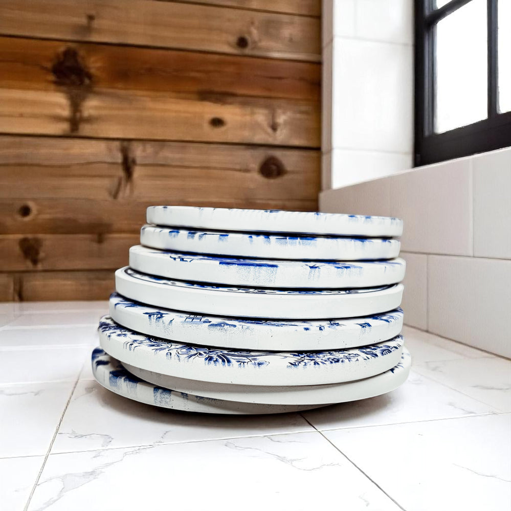 Stack of white plates with blue floral patterns on a tiled floor.