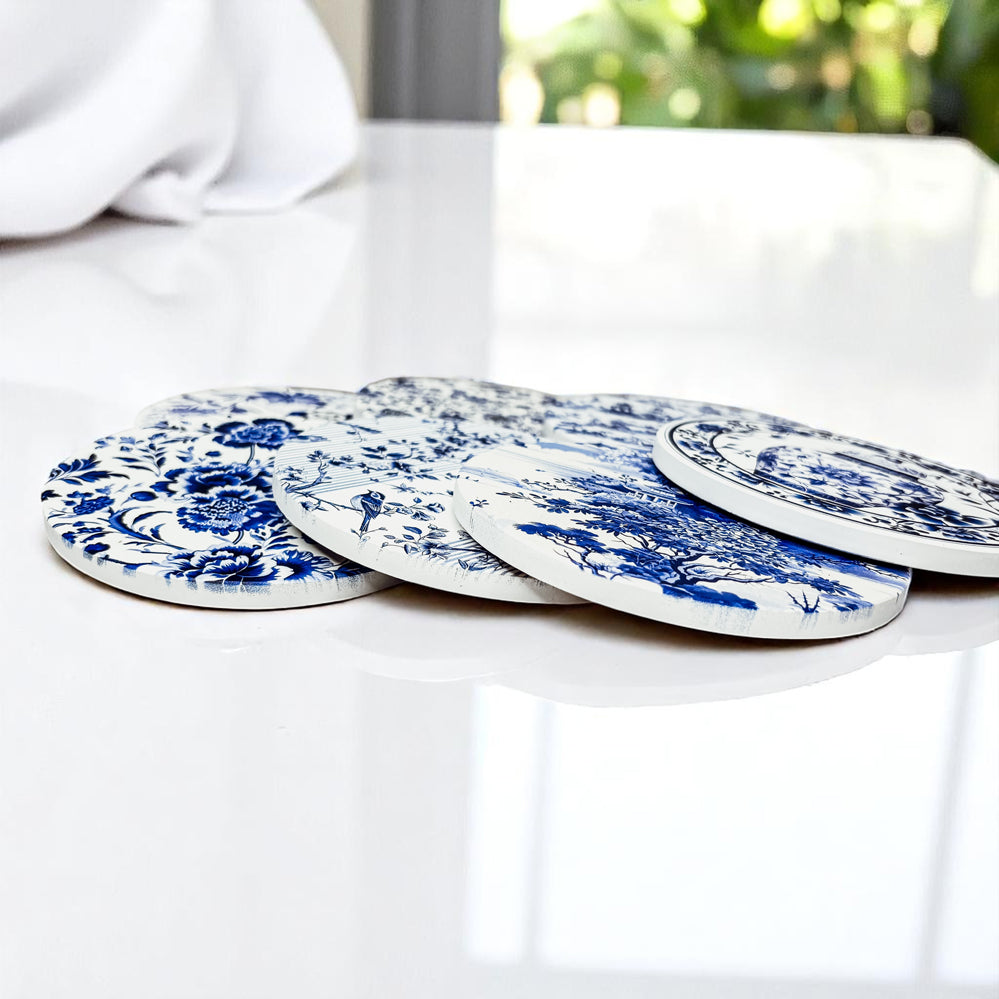 Set of blue and white ceramic coasters on a white surface with a blurred outdoor background.