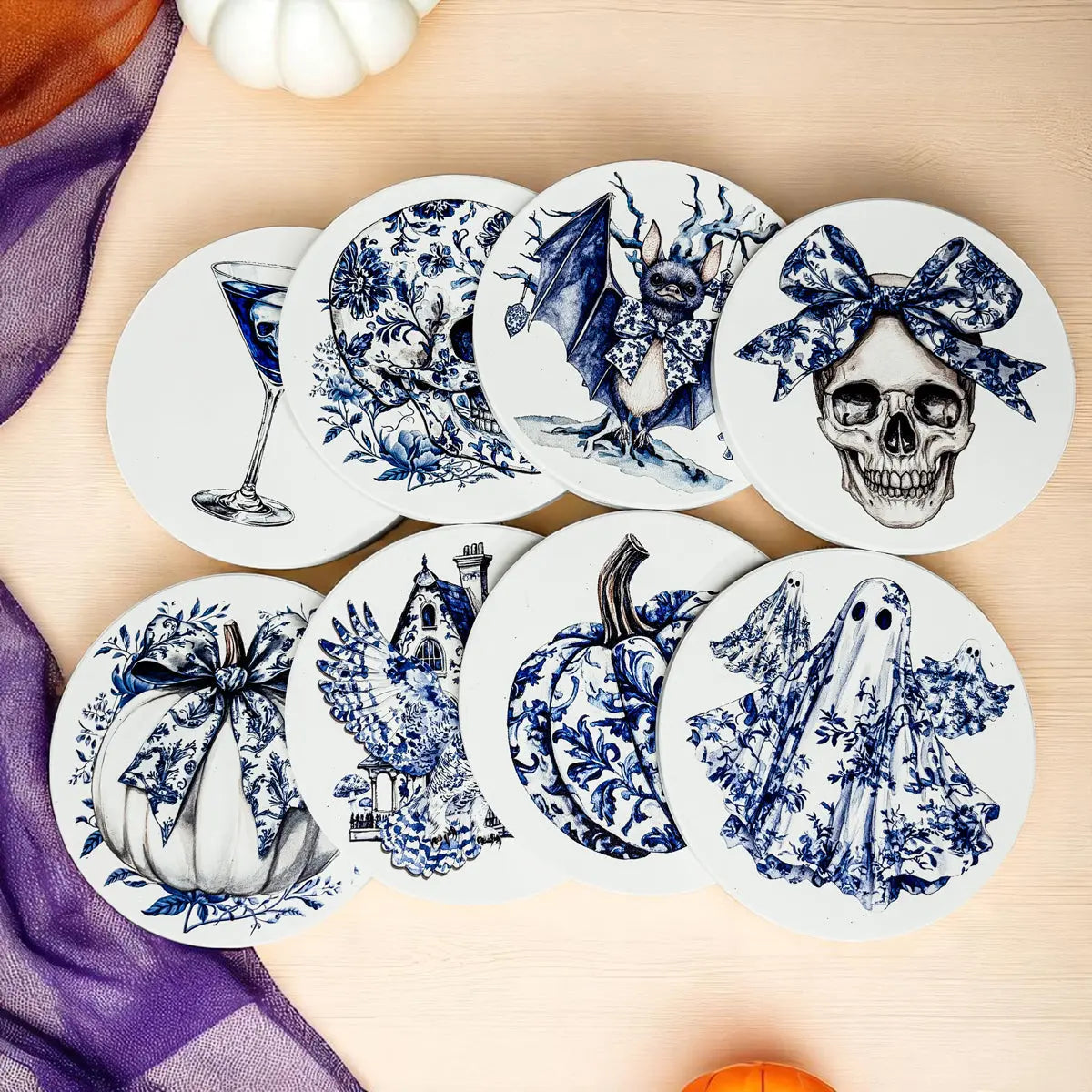 Set of Halloween-themed coasters with blue and white designs on a wooden surface.