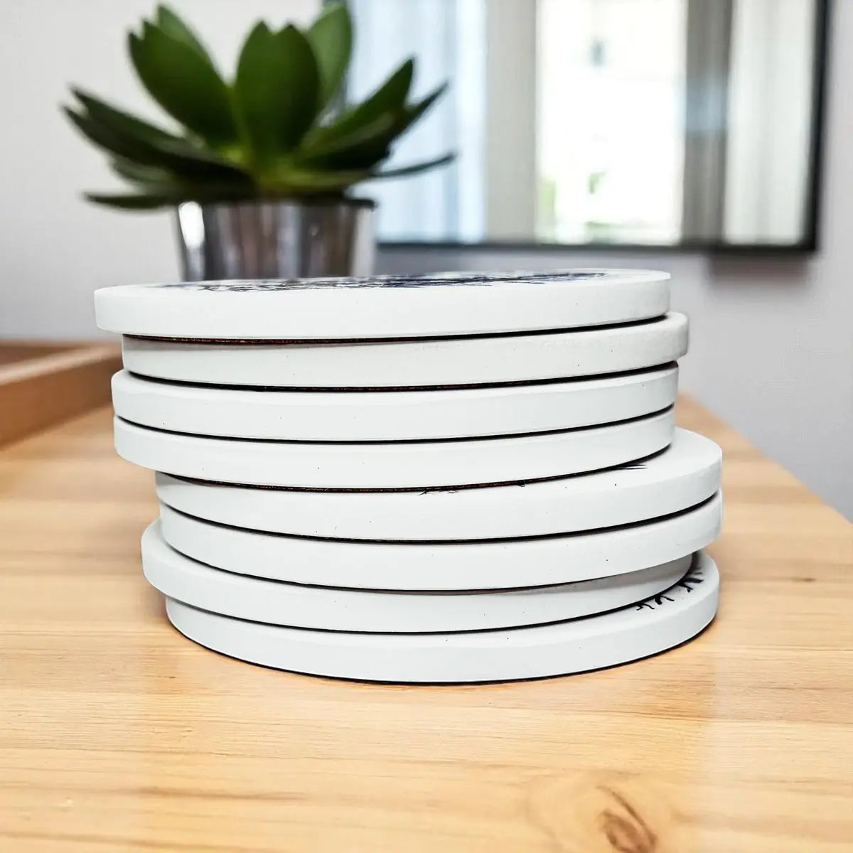 Stack of white circular objects on a wooden surface with a plant in the background