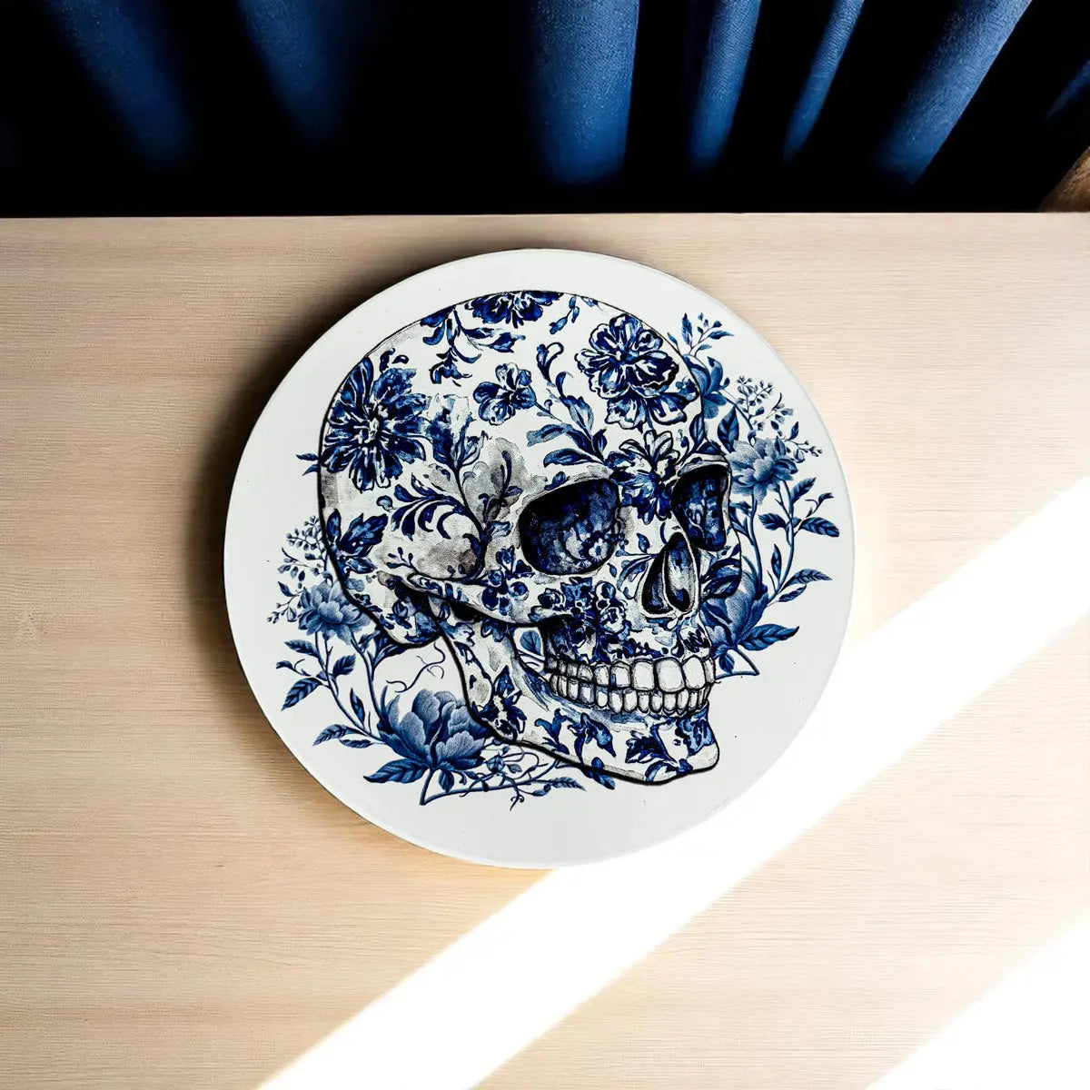 Round coaster with a blue floral skull design on a wooden surface
