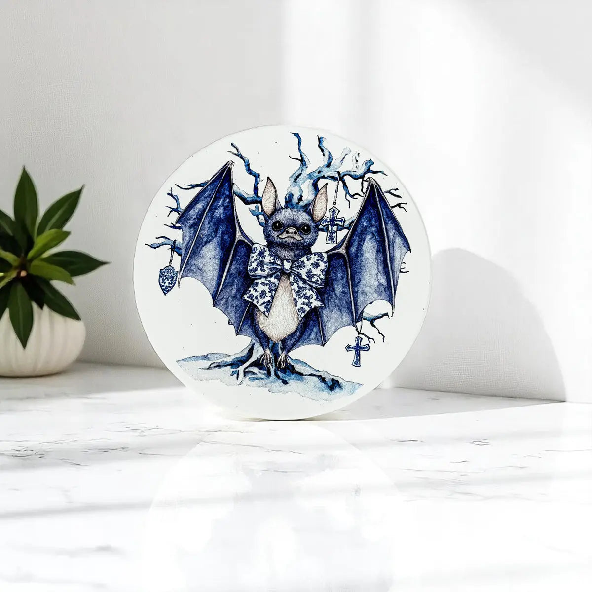 Round coaster with a bat illustration on a white surface with a plant in the background