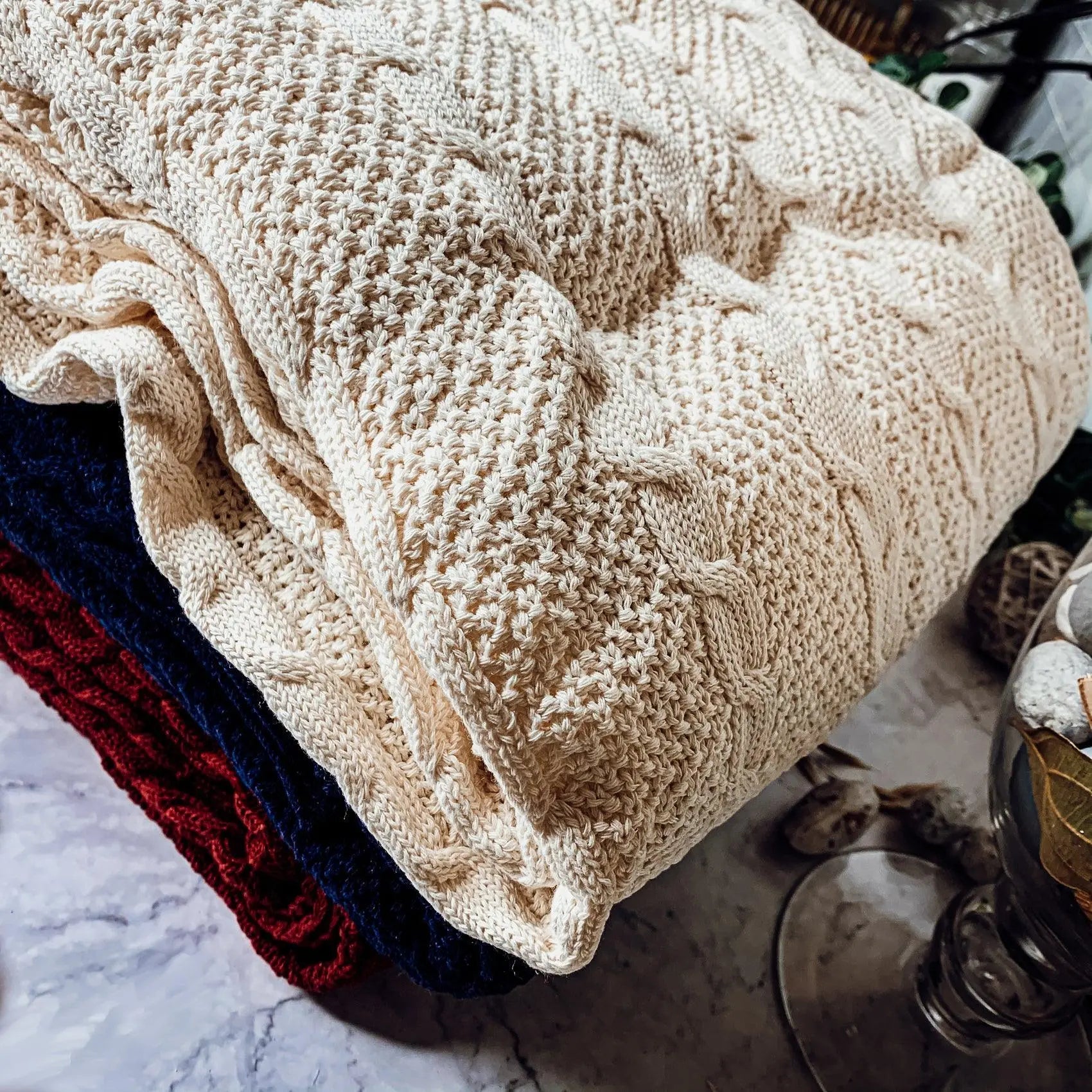 Cozy cable knit blanket in cream, navy, and red for farmhouse-style home decor