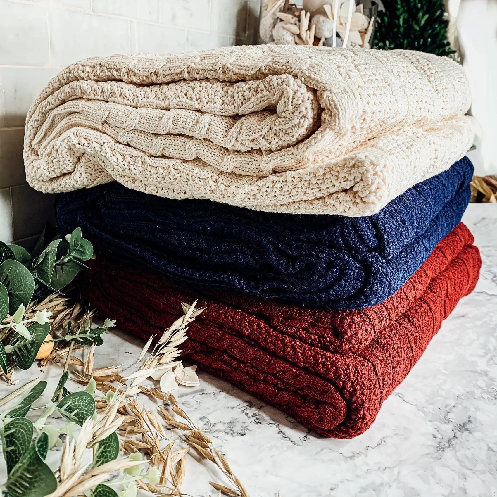 Cozy cable knit blankets in cream, navy, and red for farmhouse decor