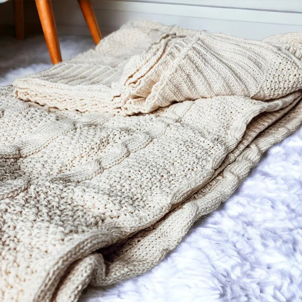 Cozy cream knit blanket with cable pattern, perfect for farmhouse or cottage style decor