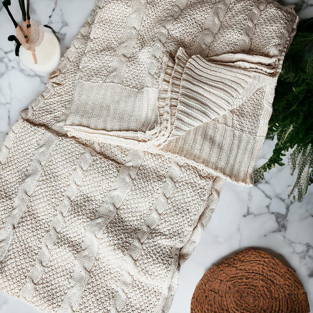 Cozy cream cable knit blanket on marble with greenery and rustic decor accents