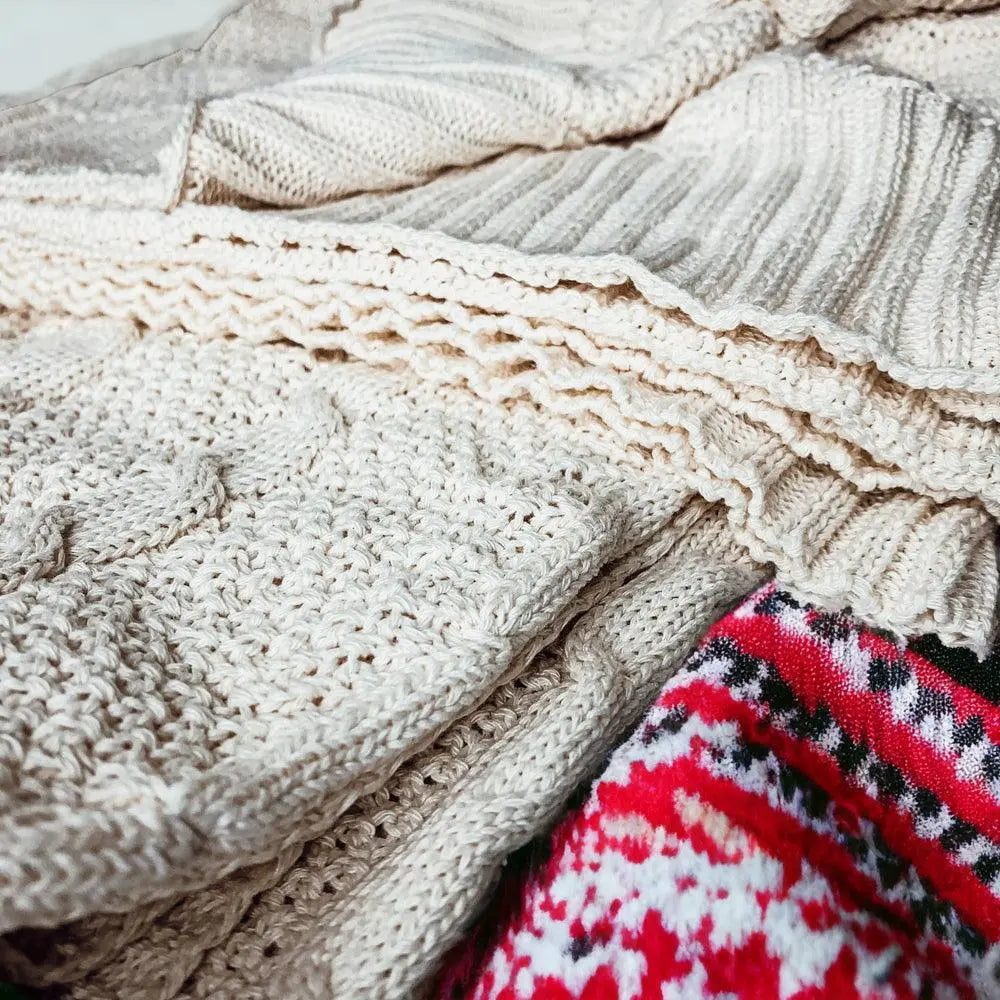 Cozy farmhouse-style knitted blankets with textured patterns and festive red accents