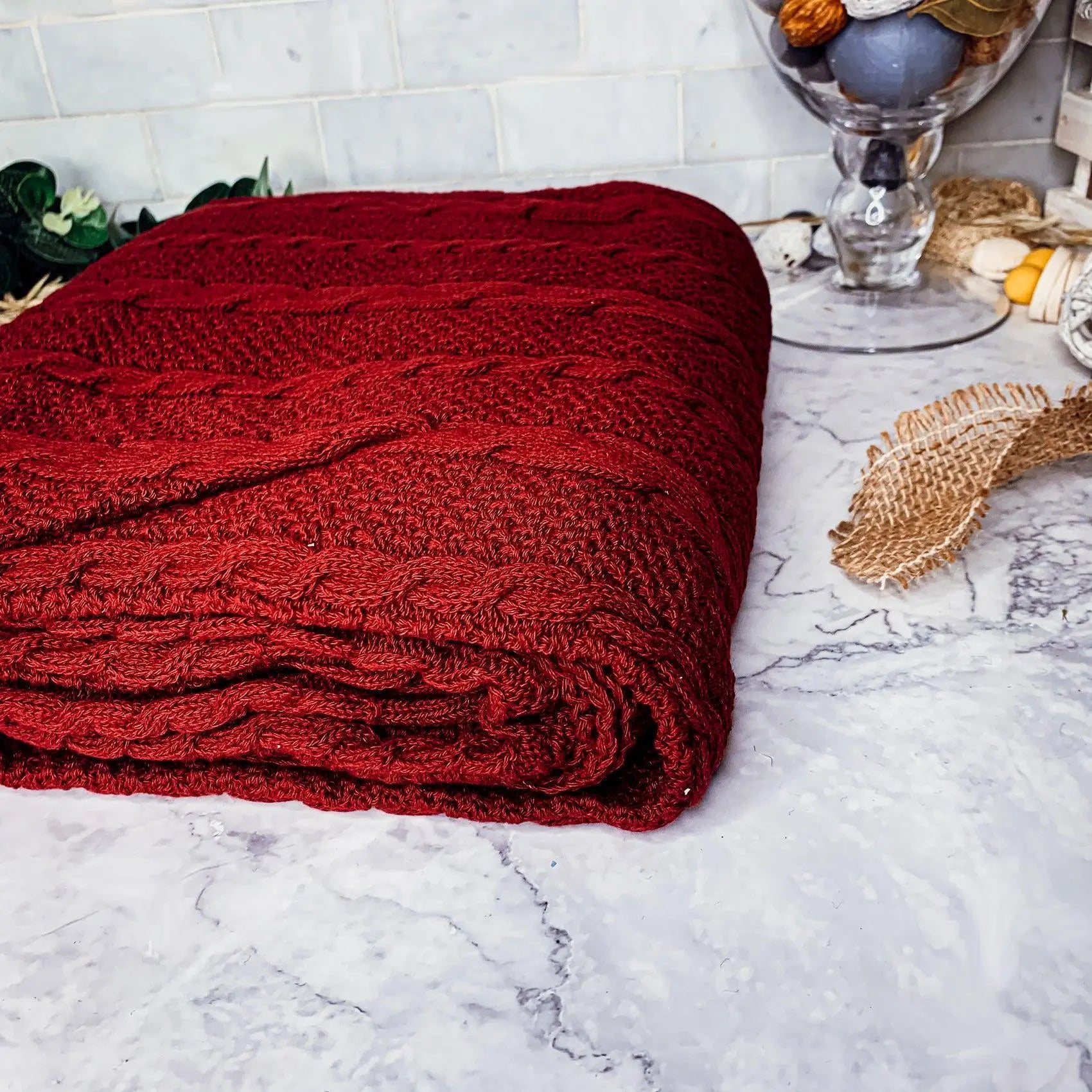 Cozy red cable knit blanket on marble countertop, farmhouse decor style