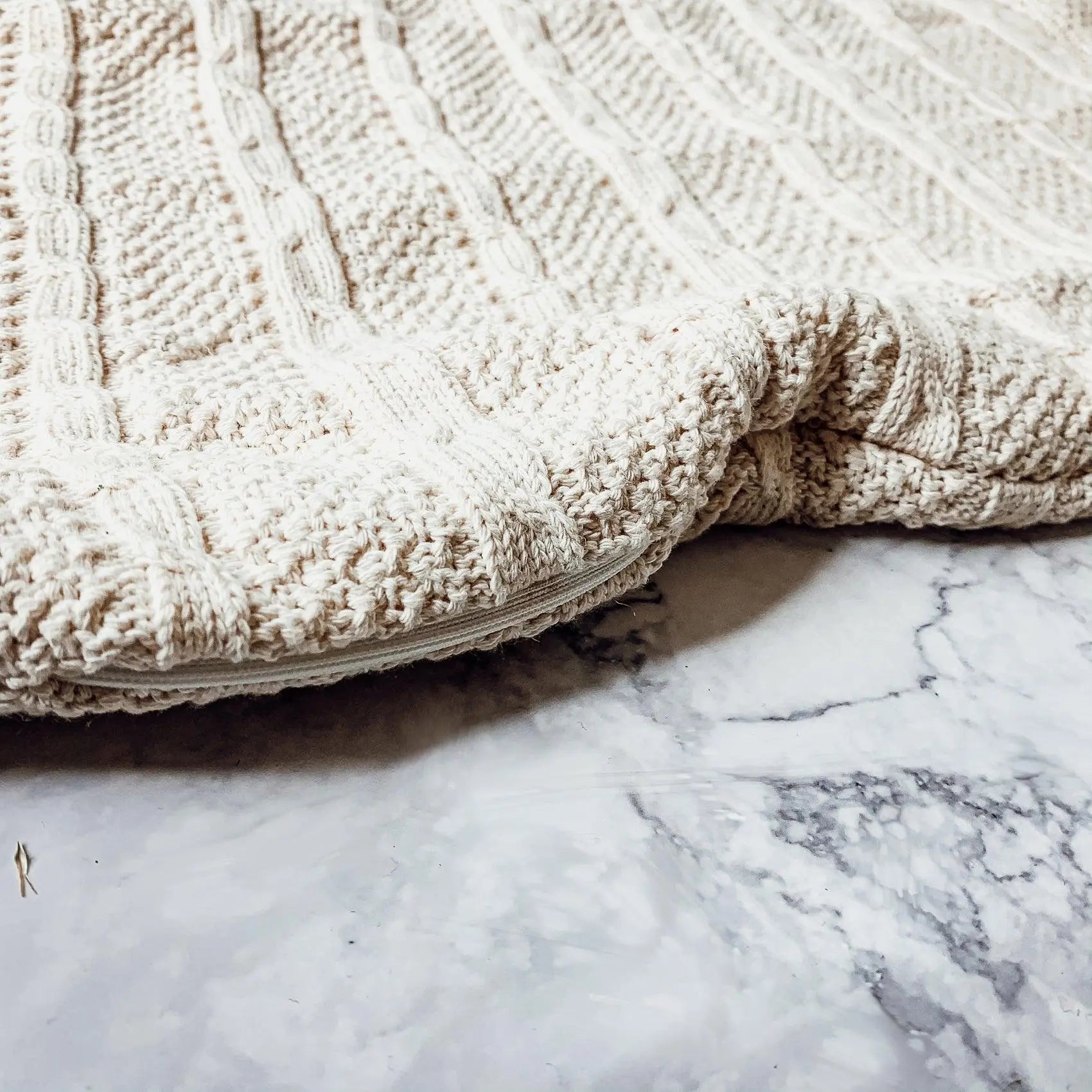 Cozy cream cable knit blanket on marble surface, farmhouse style home decor