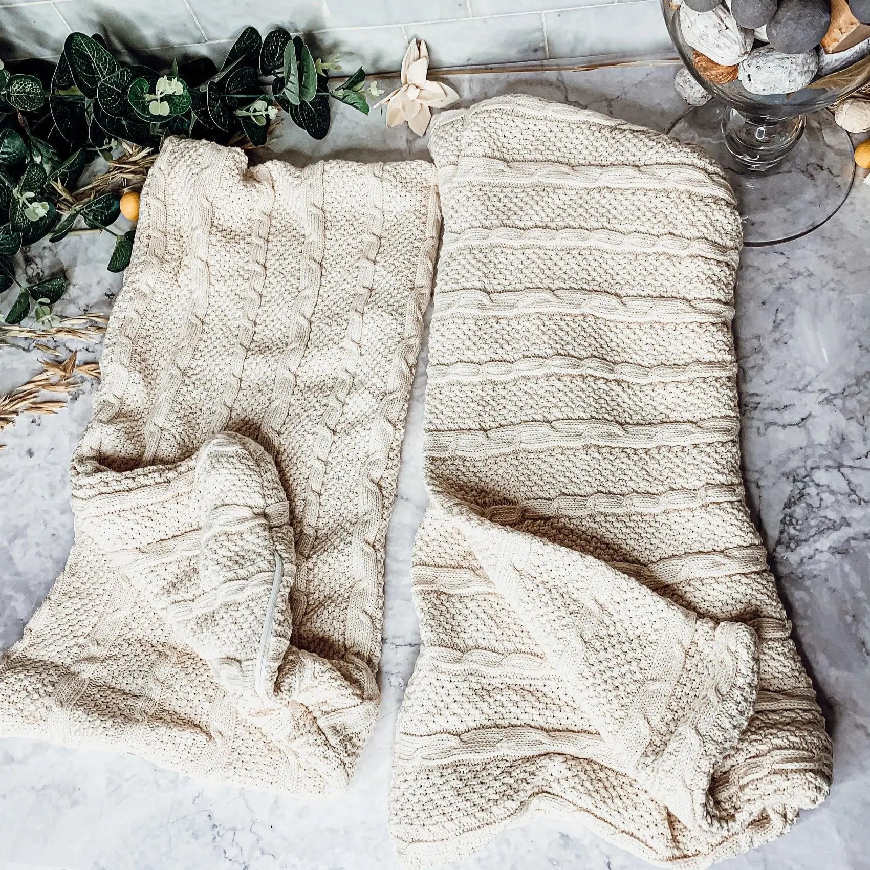 Cozy cream cable knit blankets on marble with greenery, perfect for farmhouse decor