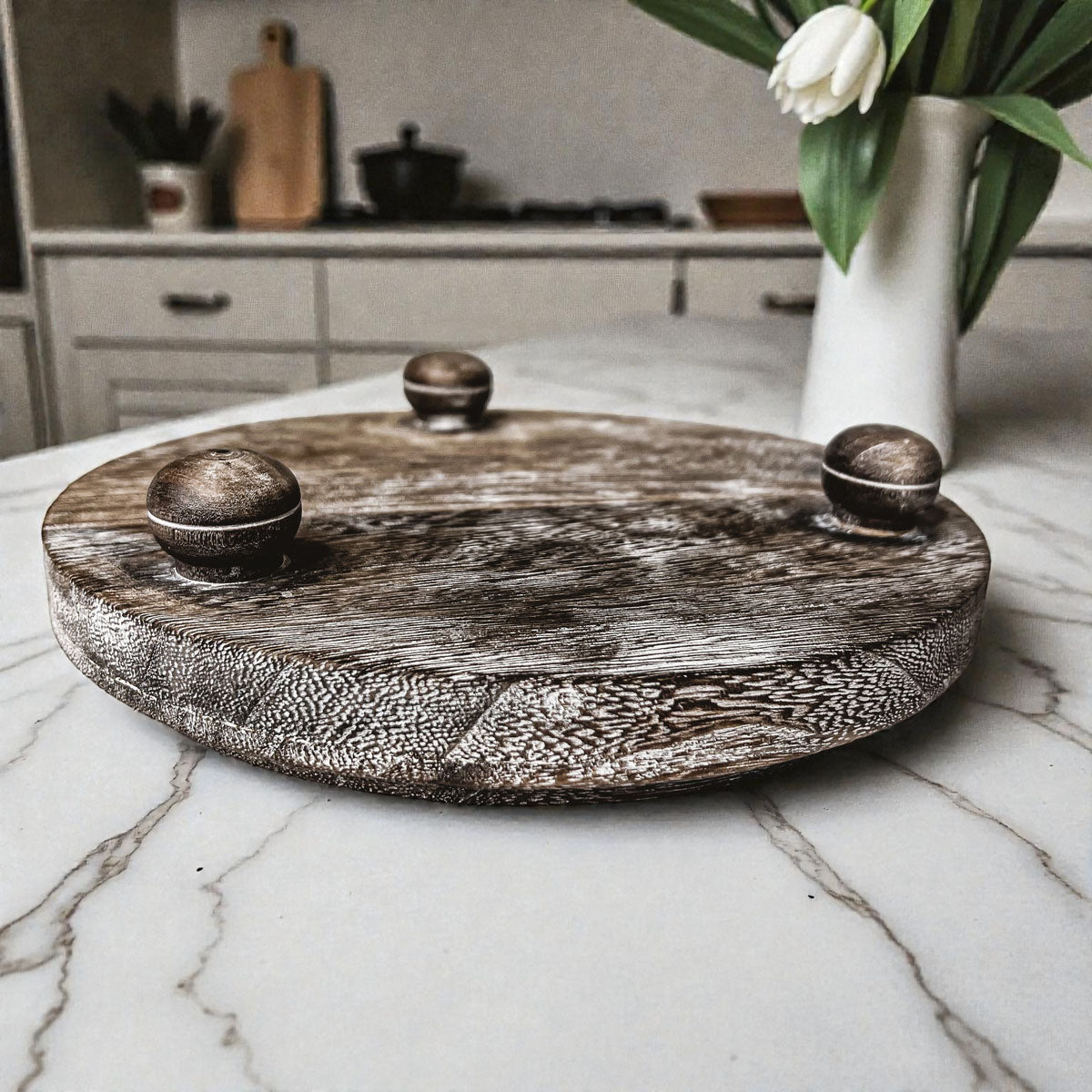 Wooden tray with decorative handles on a marble countertop in a kitchen setting.