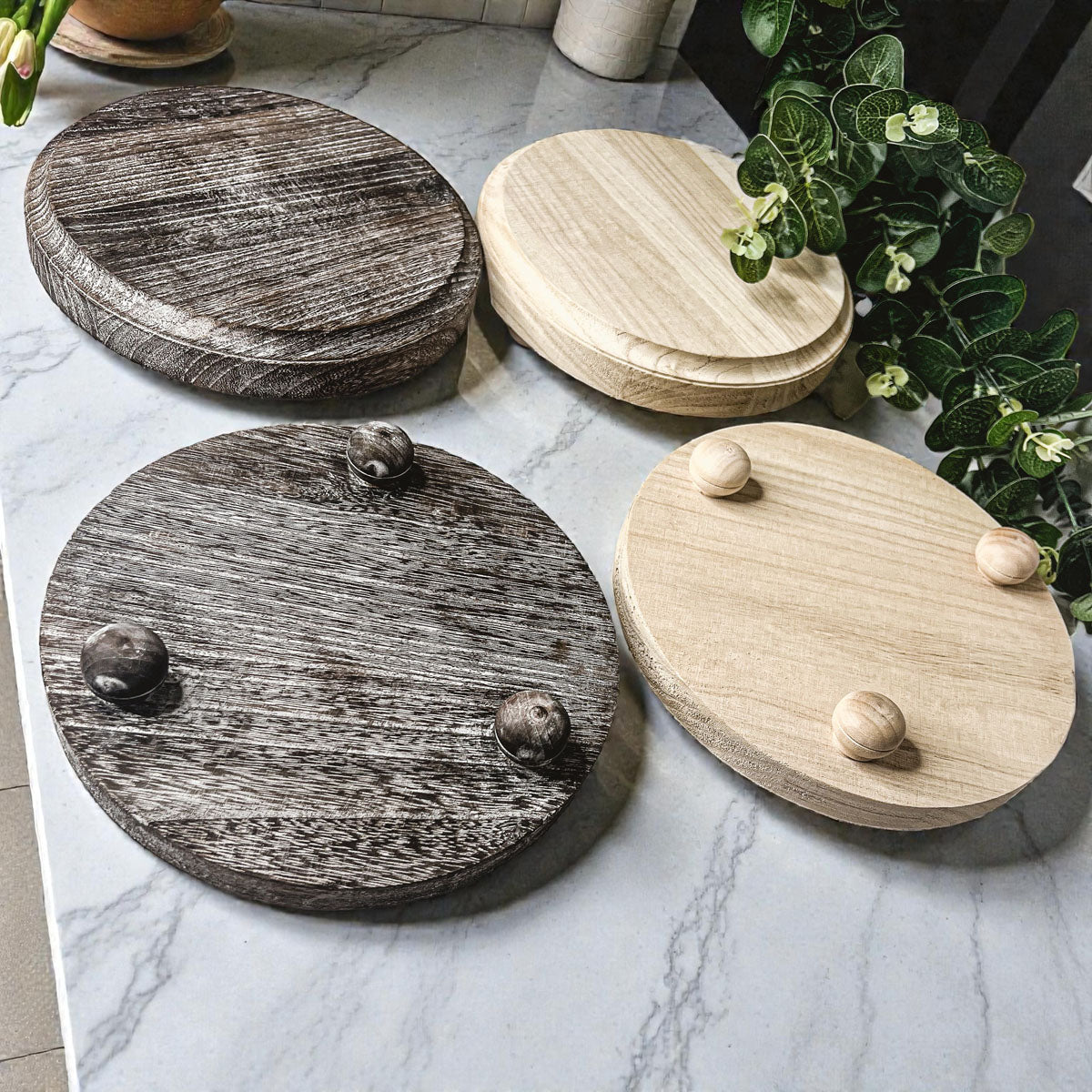 Set of wooden coasters with decorative knobs on a marble surface.