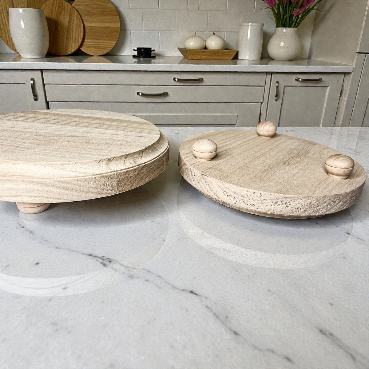 Two wooden trays with decorative elements on a marble countertop.